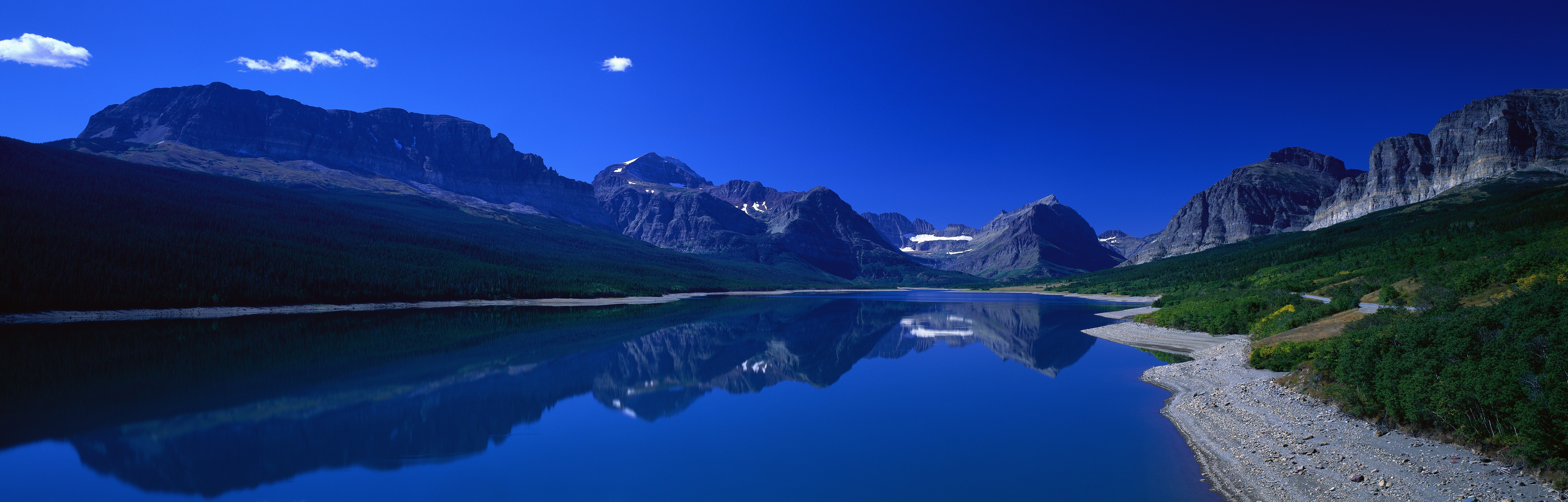 Mountains reflected in a calm lake under a clear blue sky HD Wallpaper