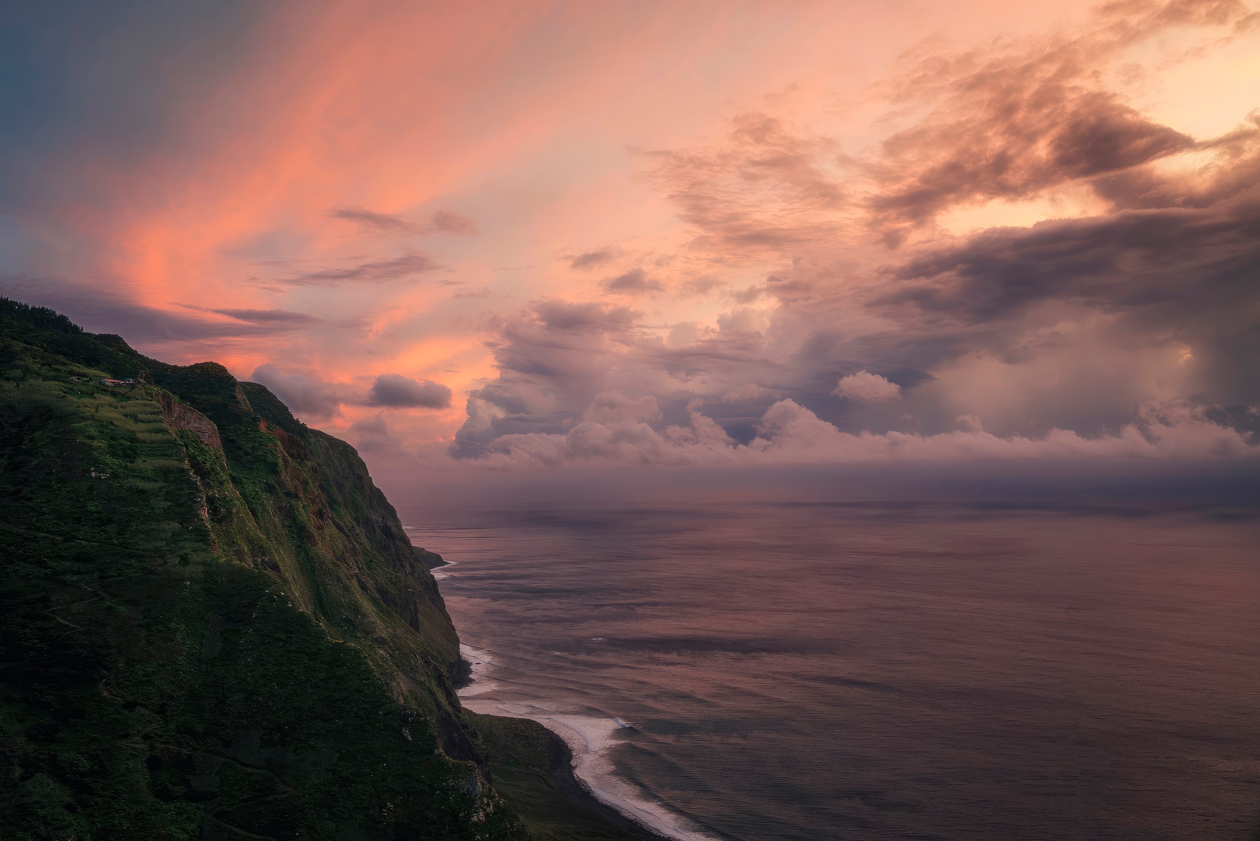 Dramatic sunset over a rugged coastline with ocean waves HD Wallpaper