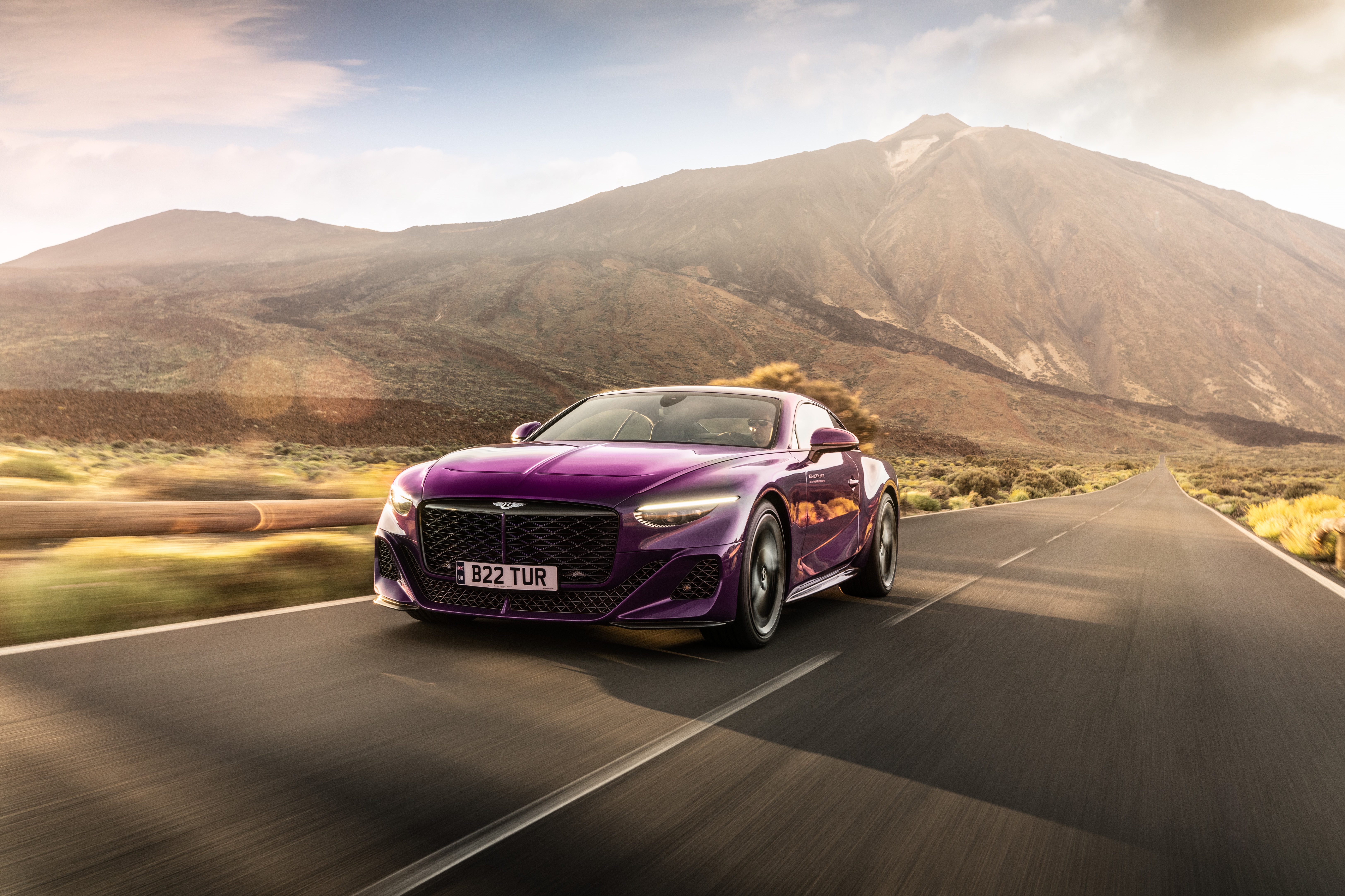 Purple Bentley Batur driving on a road with mountains HD Wallpaper