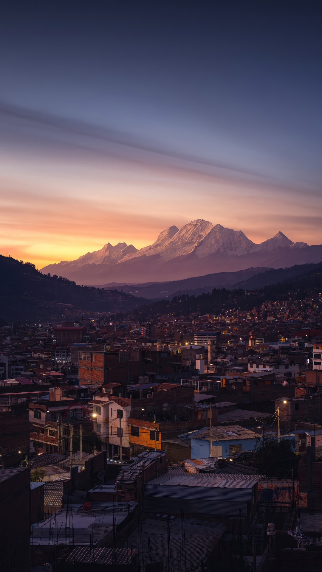 Cityscape at sunset with snow-capped mountains HD Phone Wallpaper