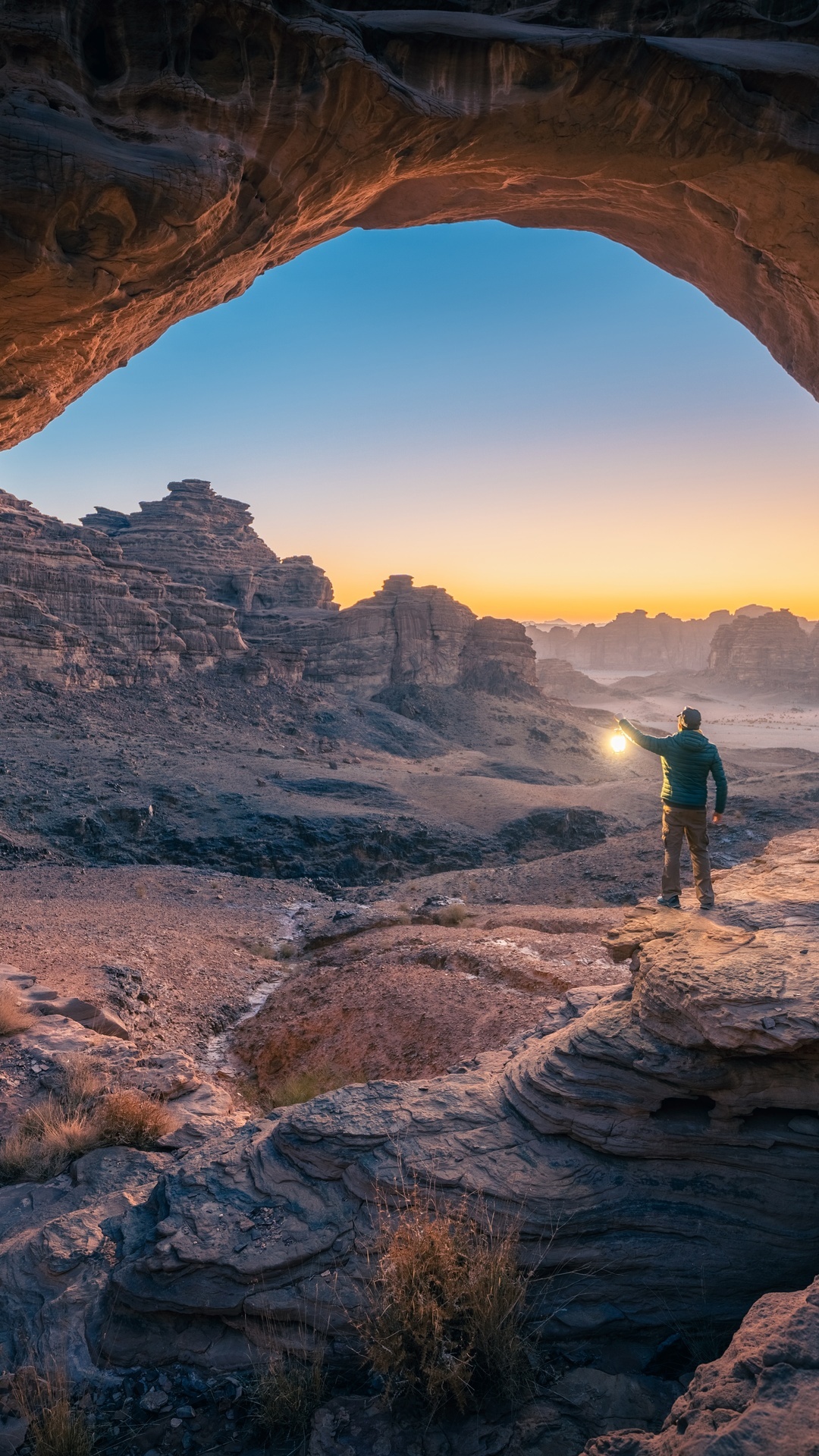 Man with lantern in desert rock formations at sunset HD Phone Wallpaper