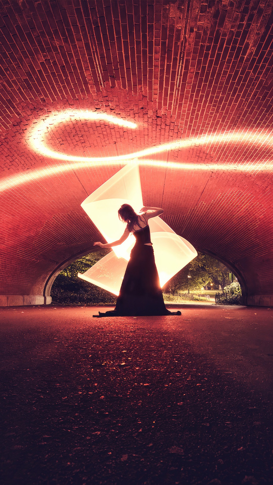 Woman in a black dress with light painting under a brick archway HD Phone Wallpaper