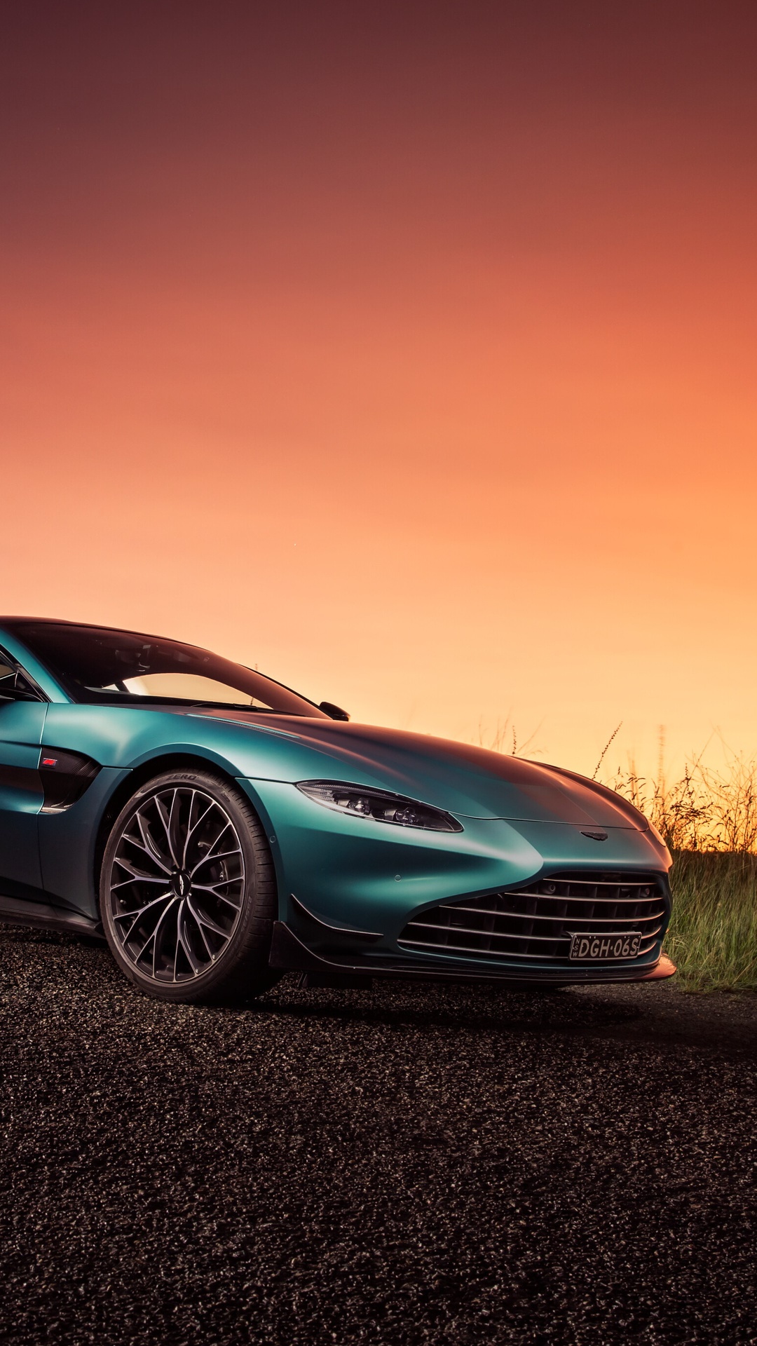 Aston Martin Vantage on a gravel road at sunset HD Phone Wallpaper