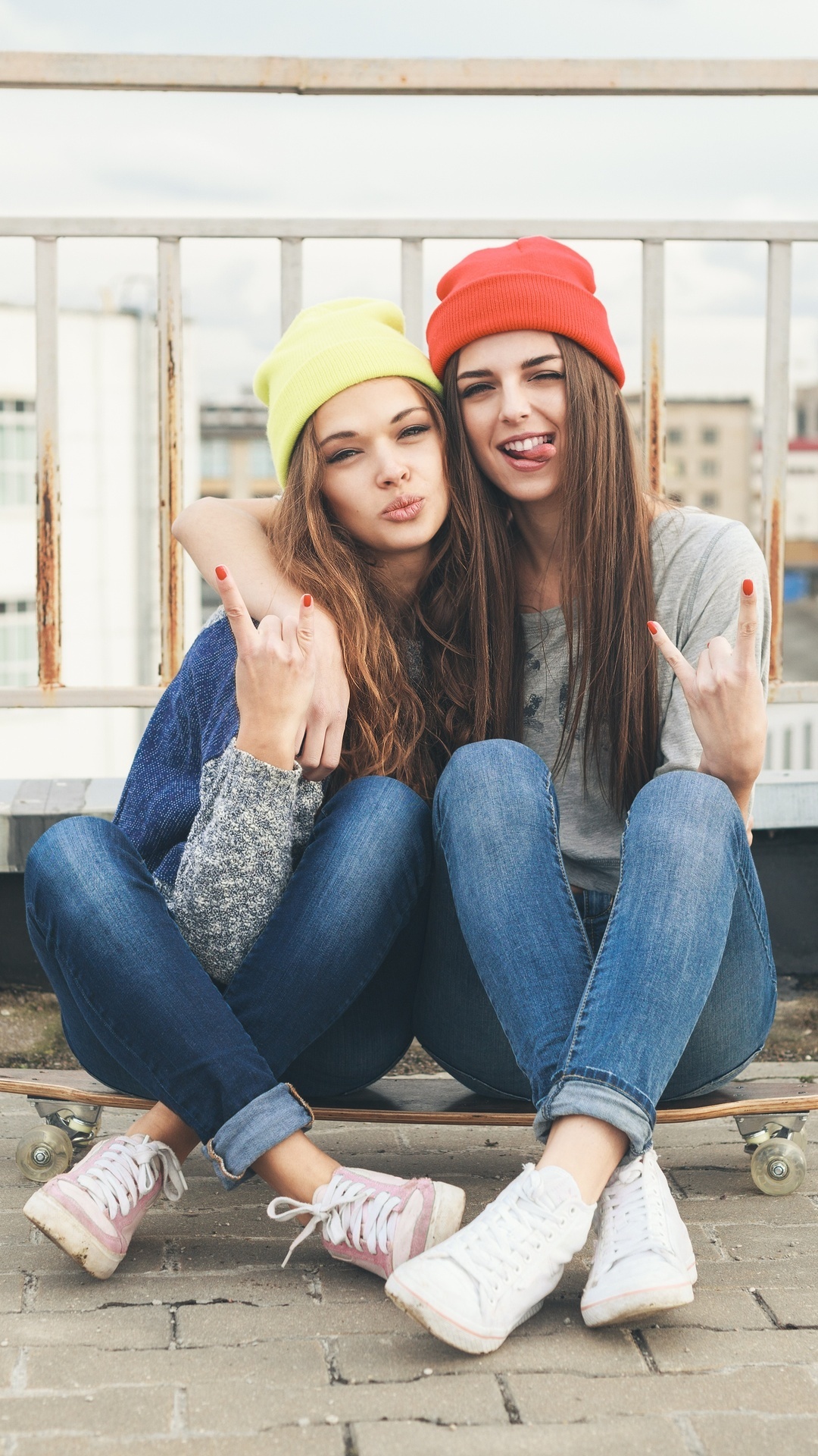 Two young women with beanies on a skateboard HD Phone Wallpaper