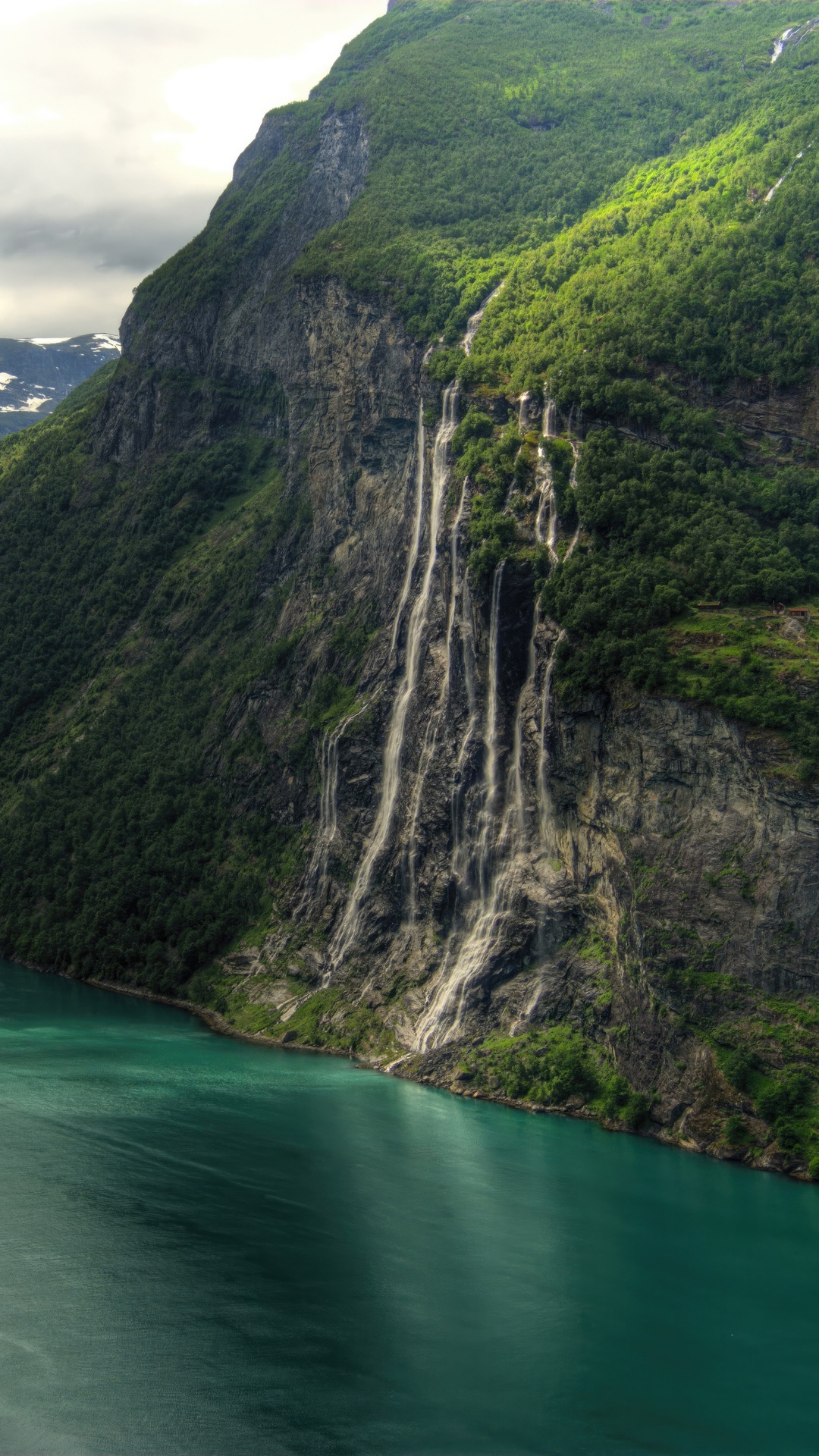 Waterfall cascading down a green mountain into a turquoise lake HD Phone Wallpaper