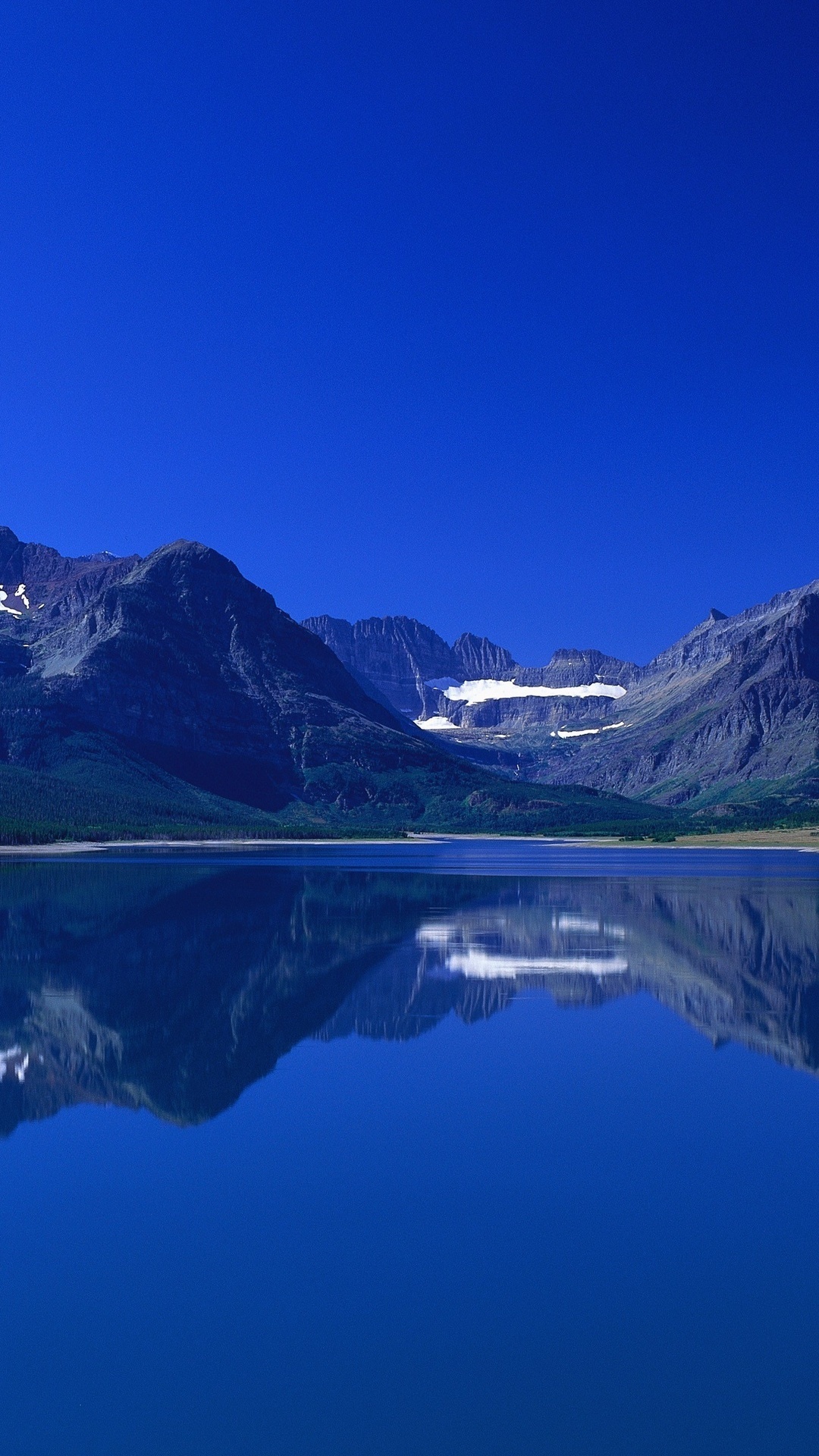 Mountains reflected in a calm lake under a clear blue sky HD Phone Wallpaper
