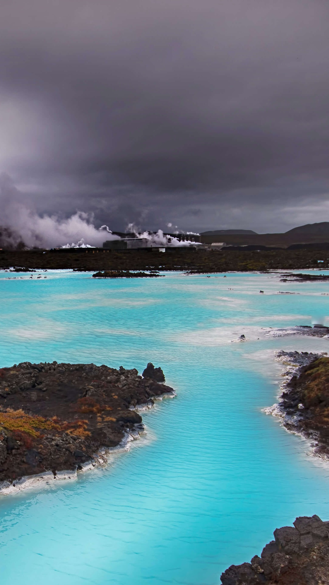 Blue Lagoon geothermal spa with steam and dark clouds HD Phone Wallpaper