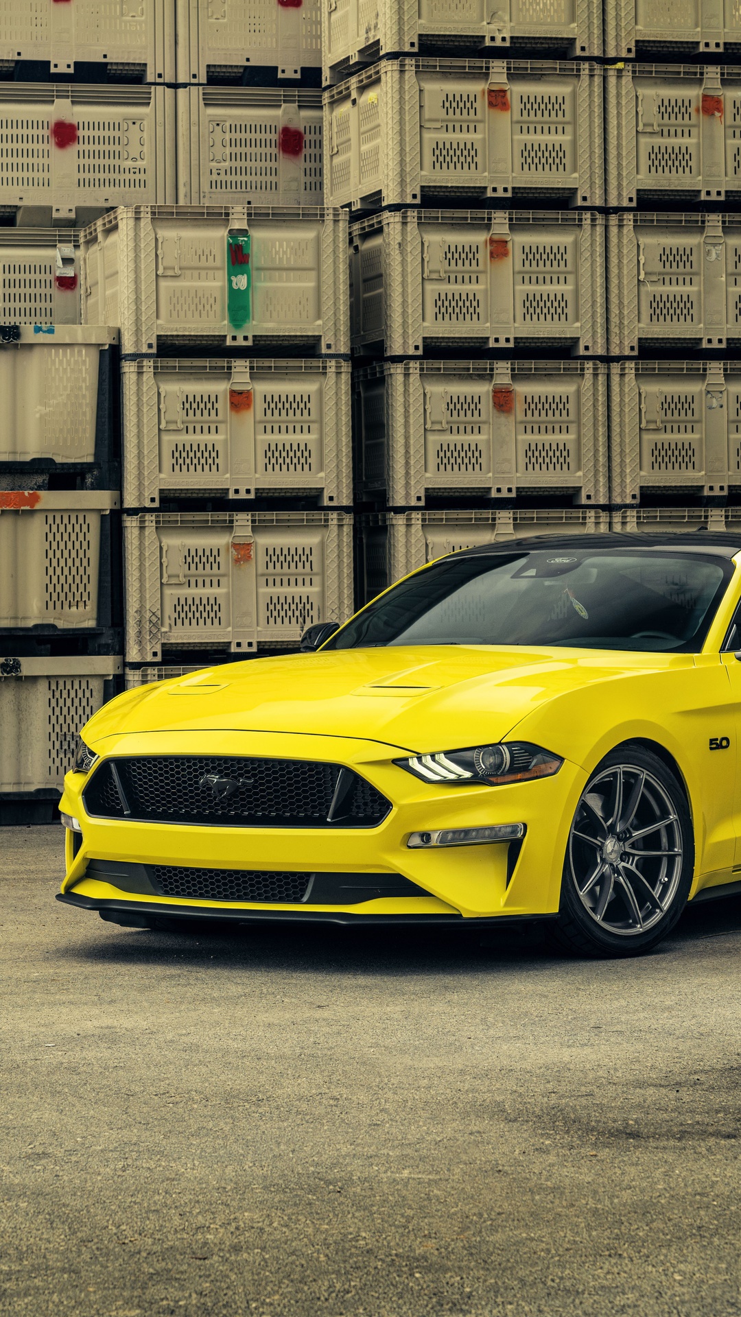 Yellow Ford Mustang parked in front of stacked crates HD Phone Wallpaper