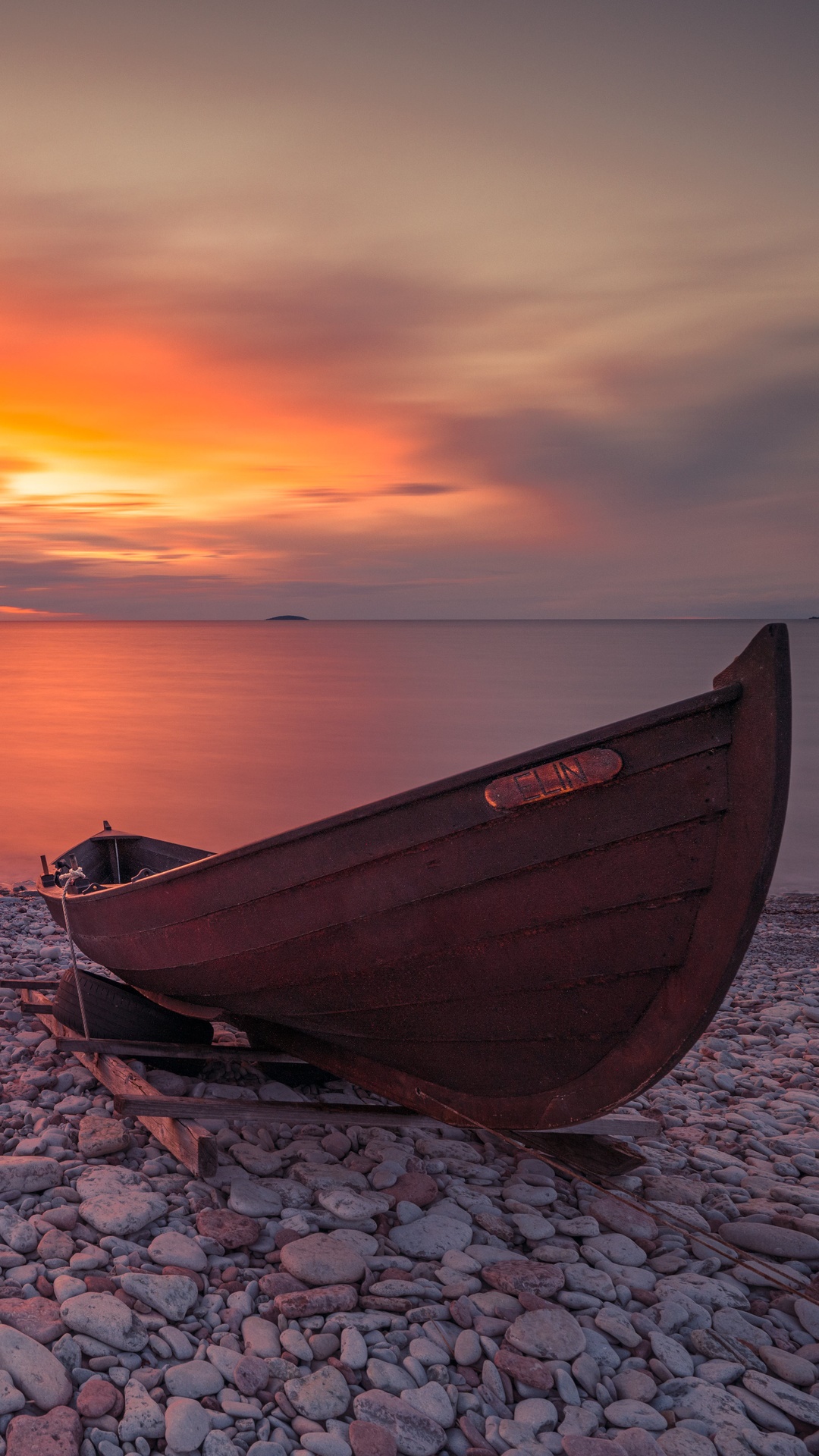 Wooden boats on a rocky shore at sunset HD Phone Wallpaper