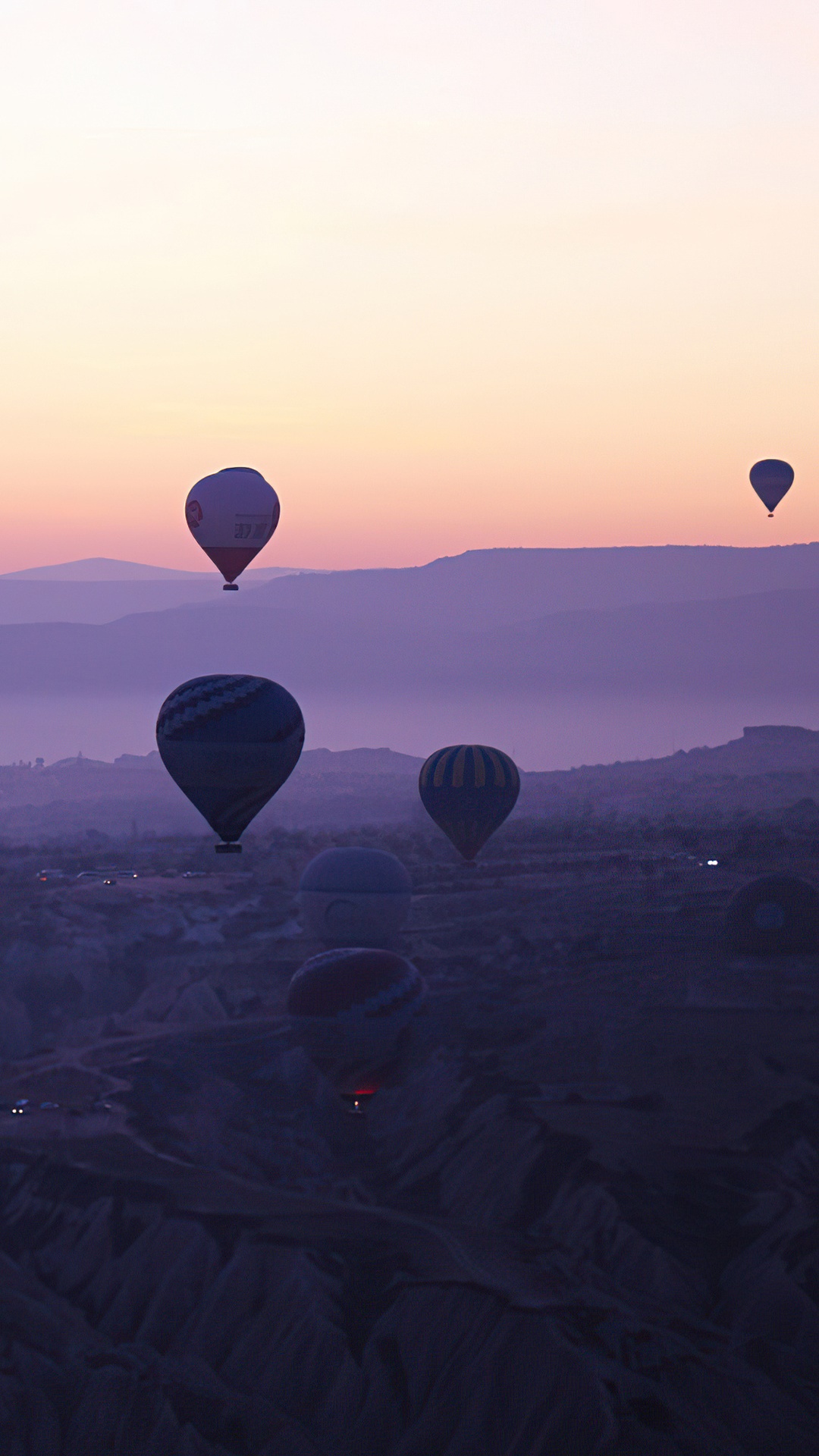 Hot air balloons at sunset over a mountainous landscape HD Phone Wallpaper