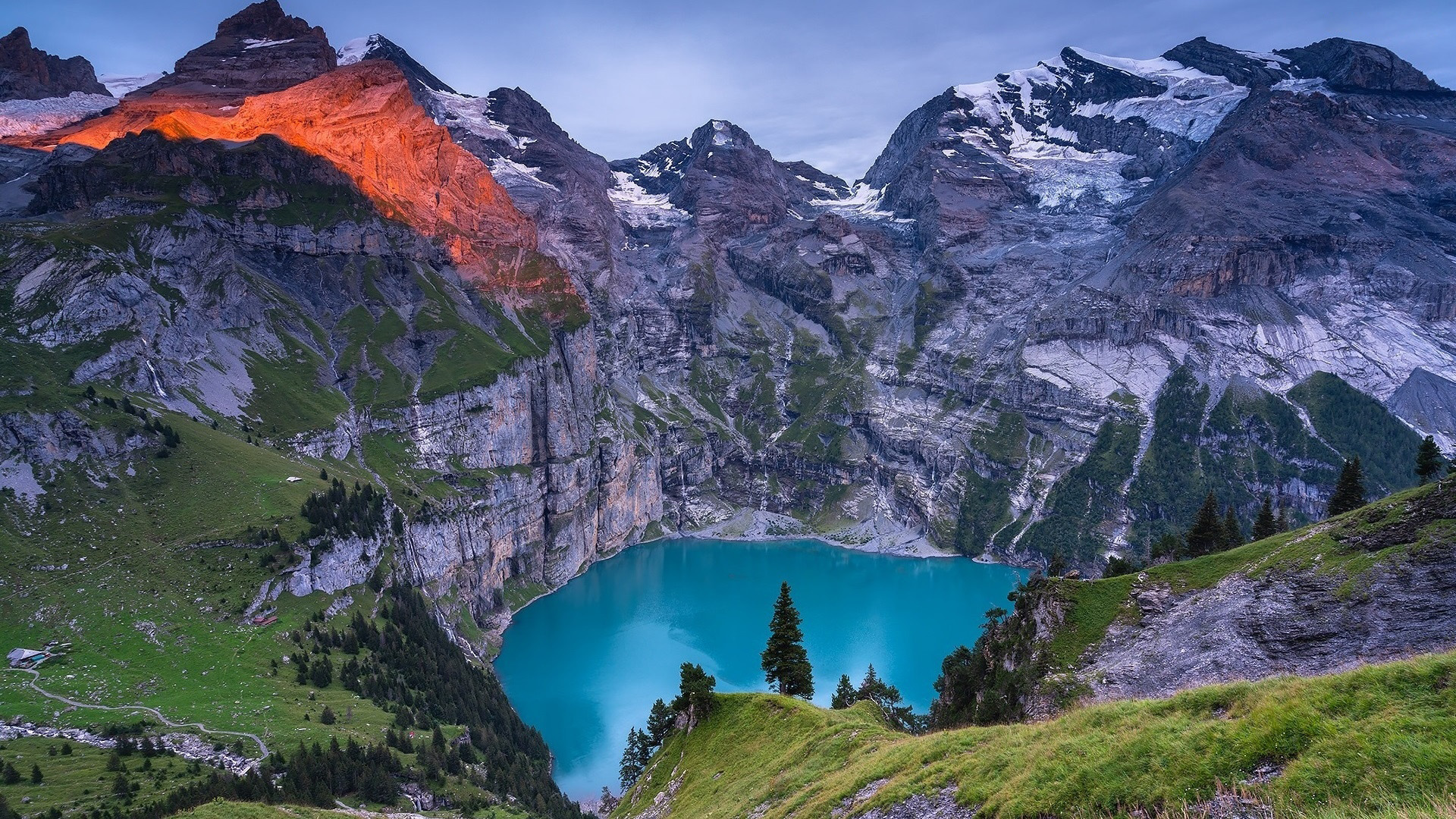 Turquoise lake surrounded by mountains and green slopes HD Wallpaper