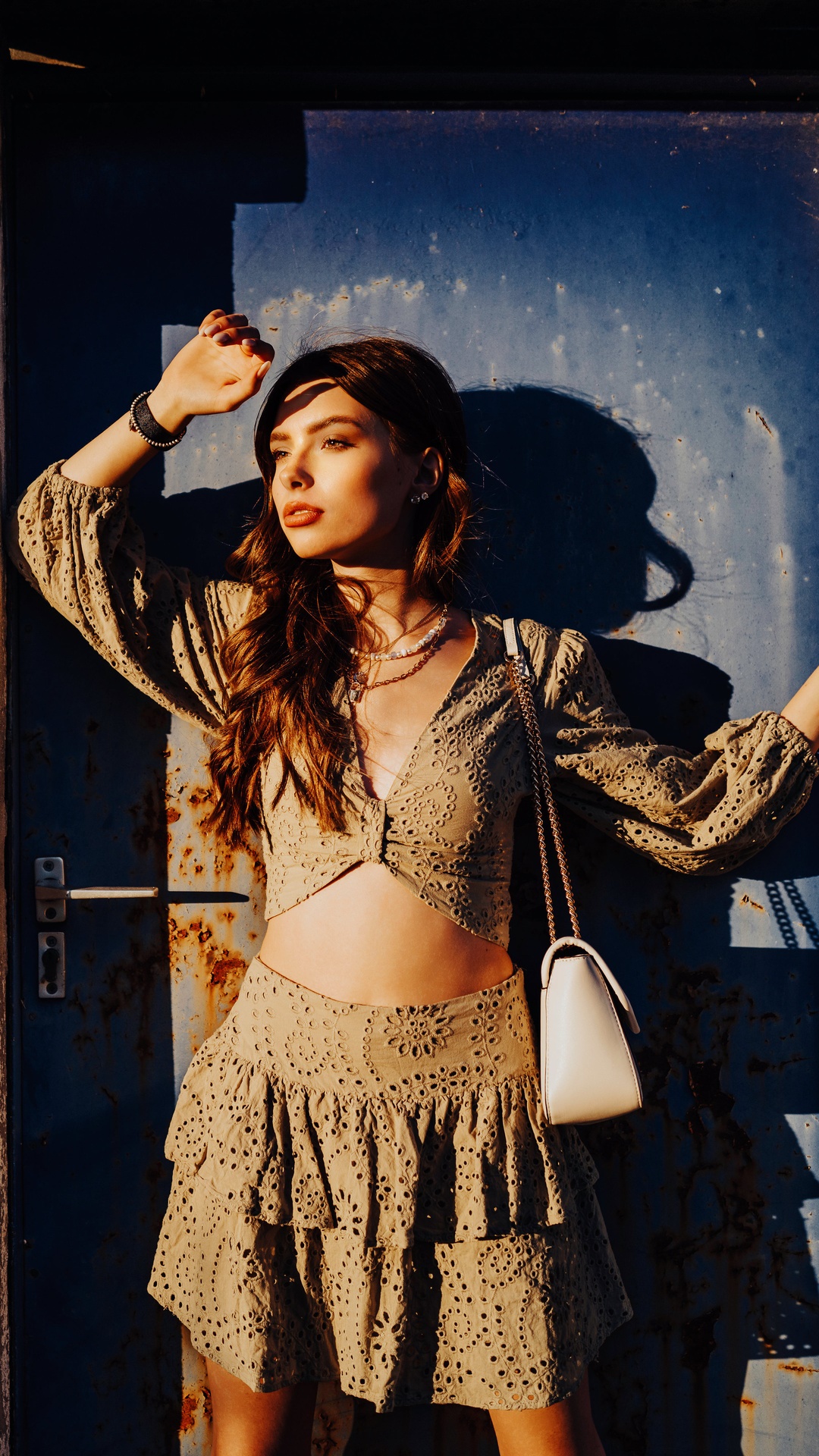 Woman in a crop top and skirt posing against a blue door HD Phone Wallpaper