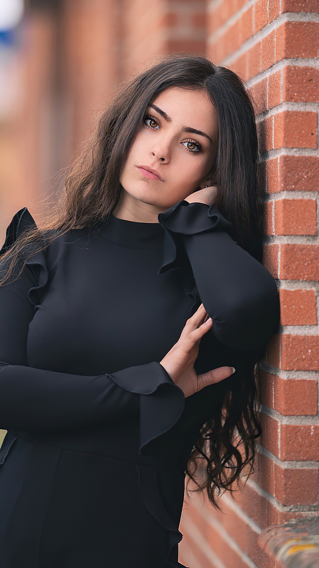 Girl in black dress leaning against brick wall HD Phone Wallpaper