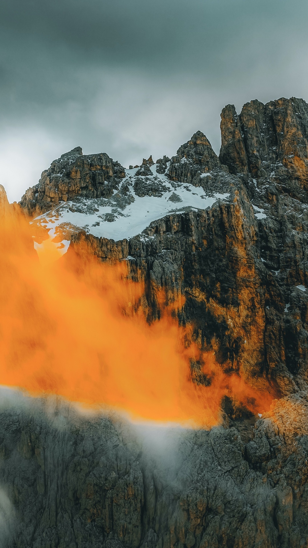 Orange clouds obscure rocky mountains with snow HD Phone Wallpaper