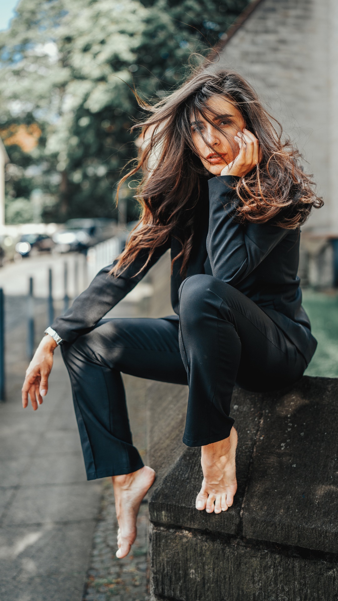 Woman in black suit sitting barefoot on stone wall HD Phone Wallpaper