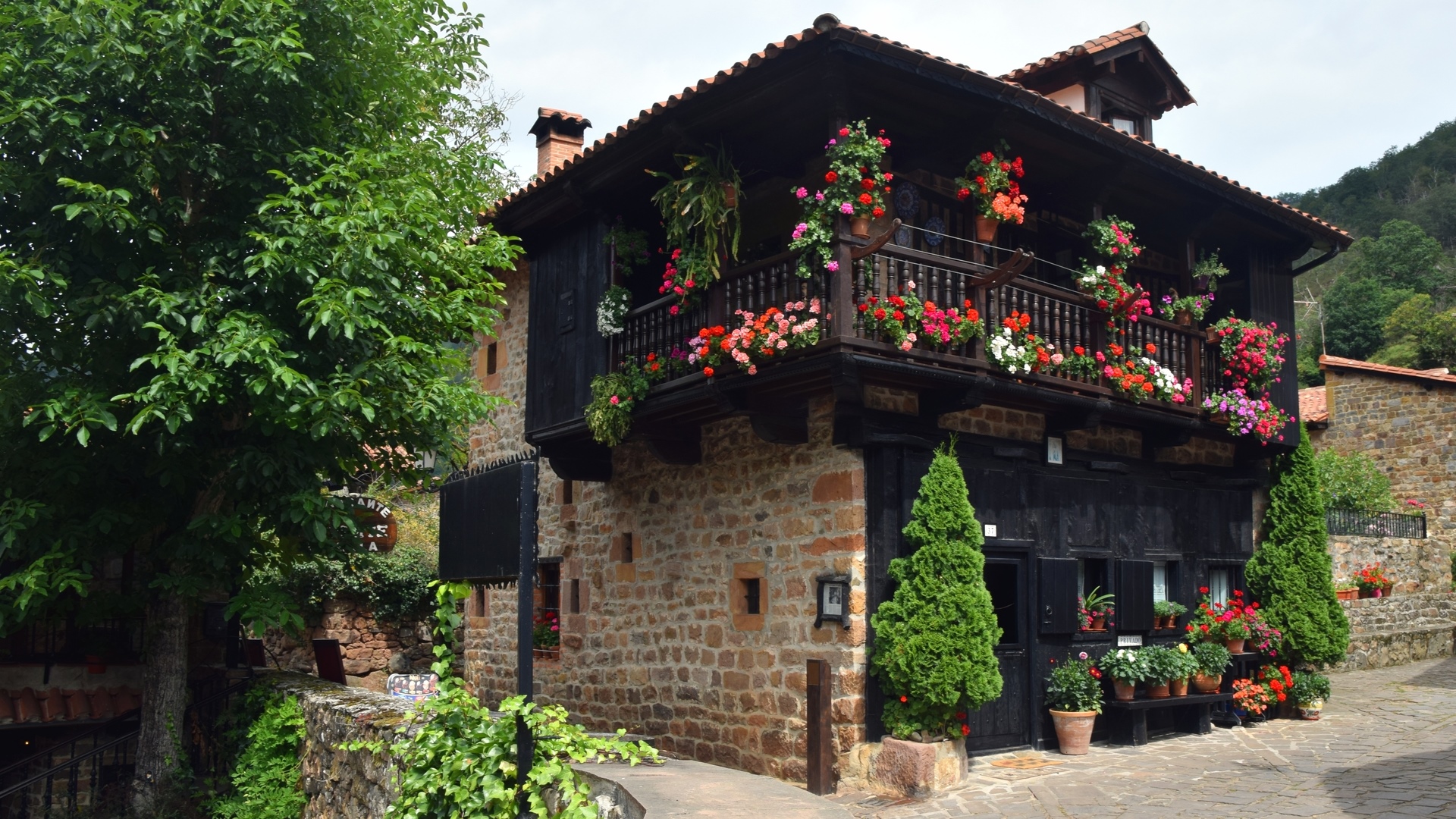 Stone house with balcony and flowers in Barcena Mayor, Spain HD Wallpaper