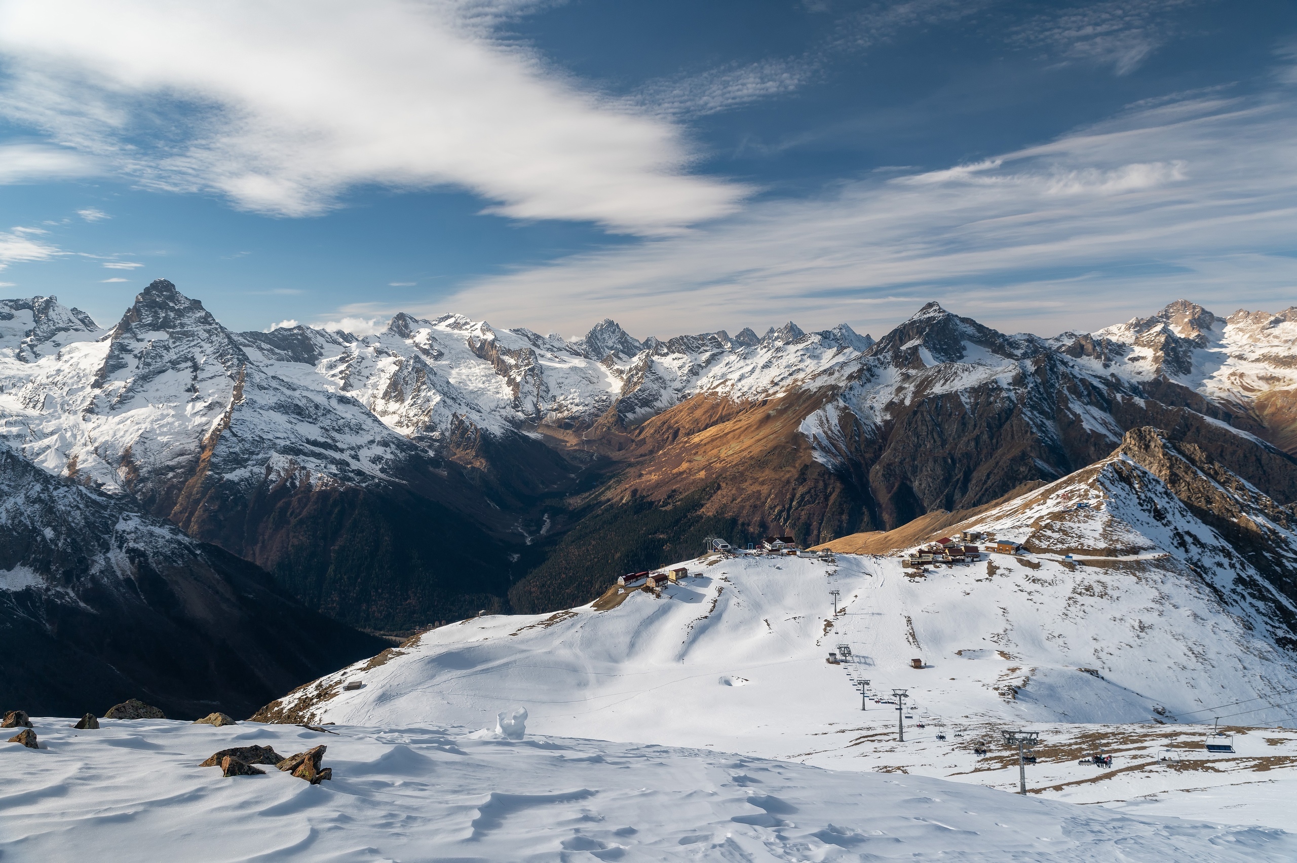 Snow-covered mountains under a cloudy blue sky HD Wallpaper