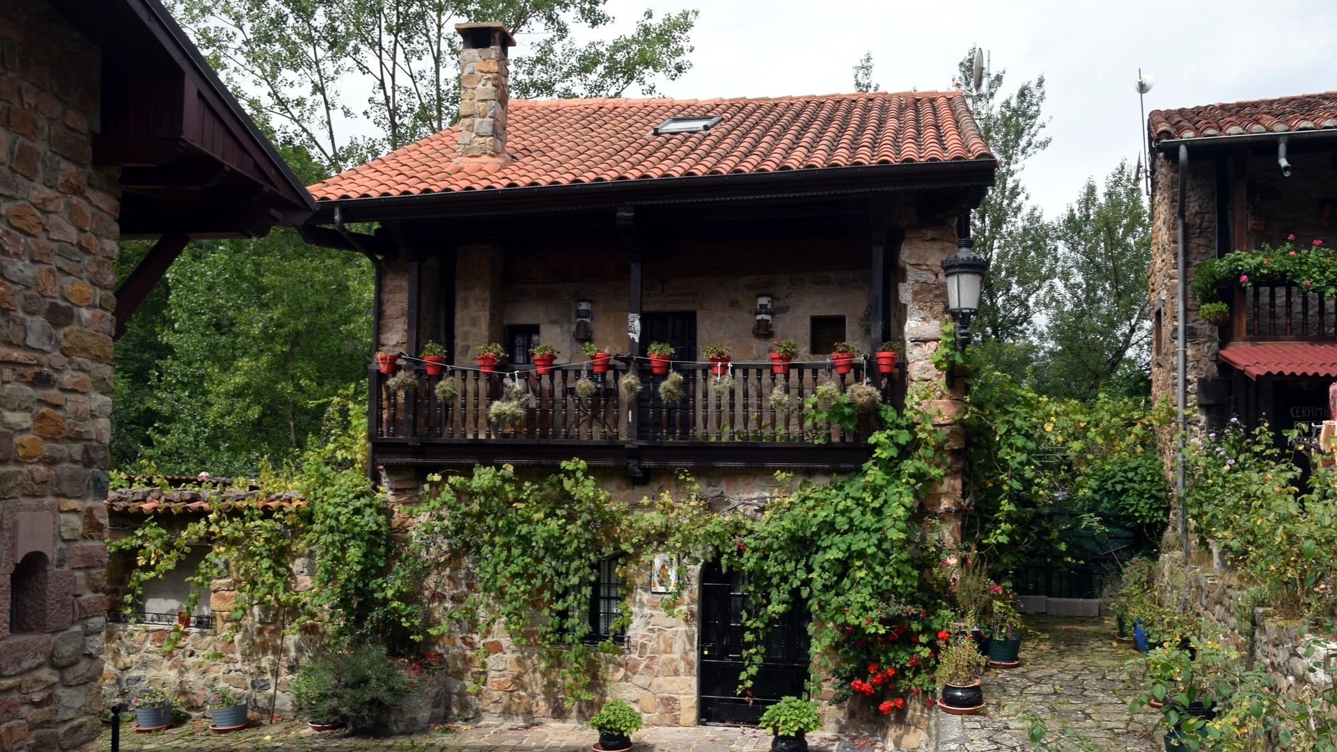 Stone building with balcony and flowers in Barcena Mayor, Spain HD Wallpaper