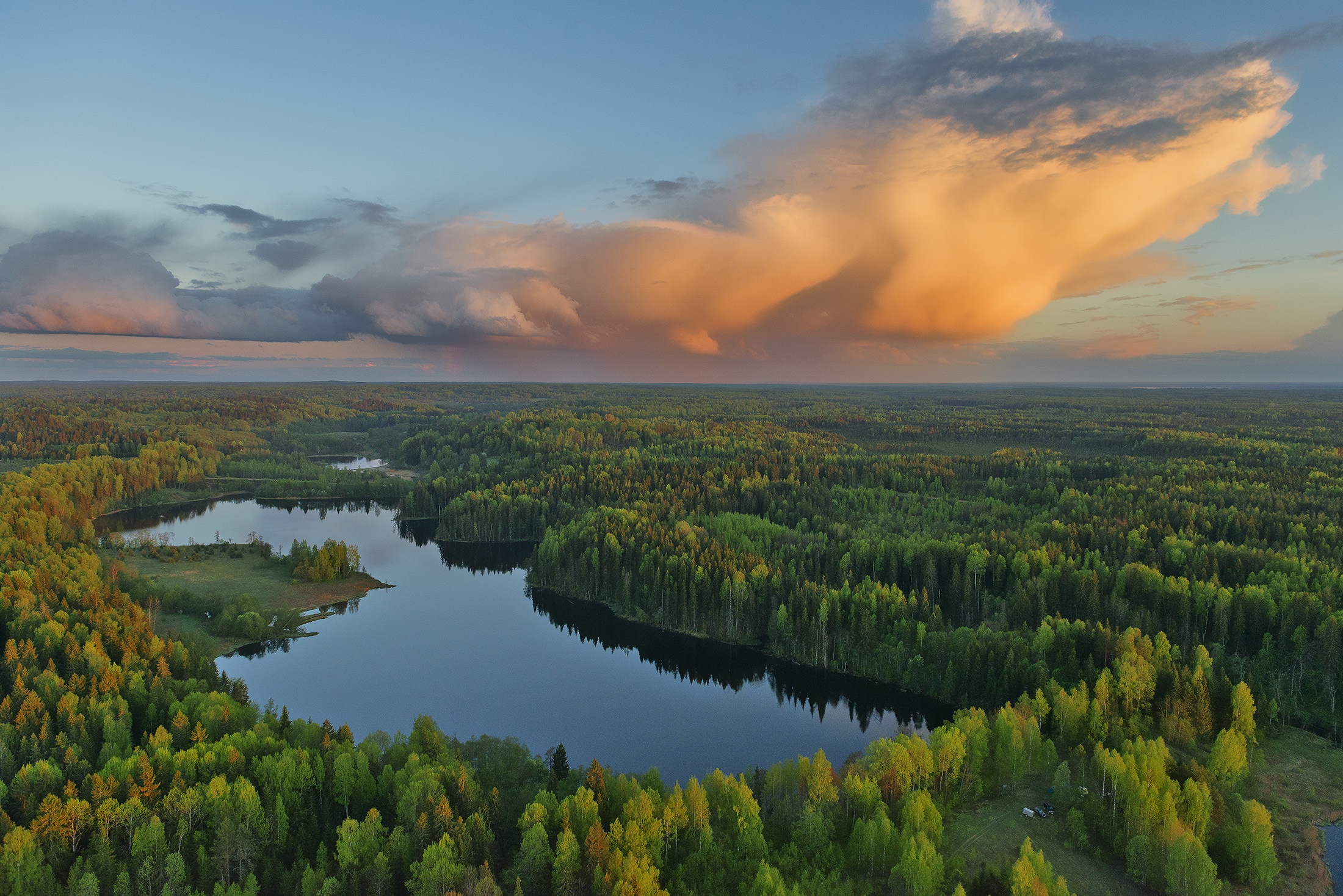 Gostilitskoe Lake surrounded by green forest under dramatic clouds HD Wallpaper