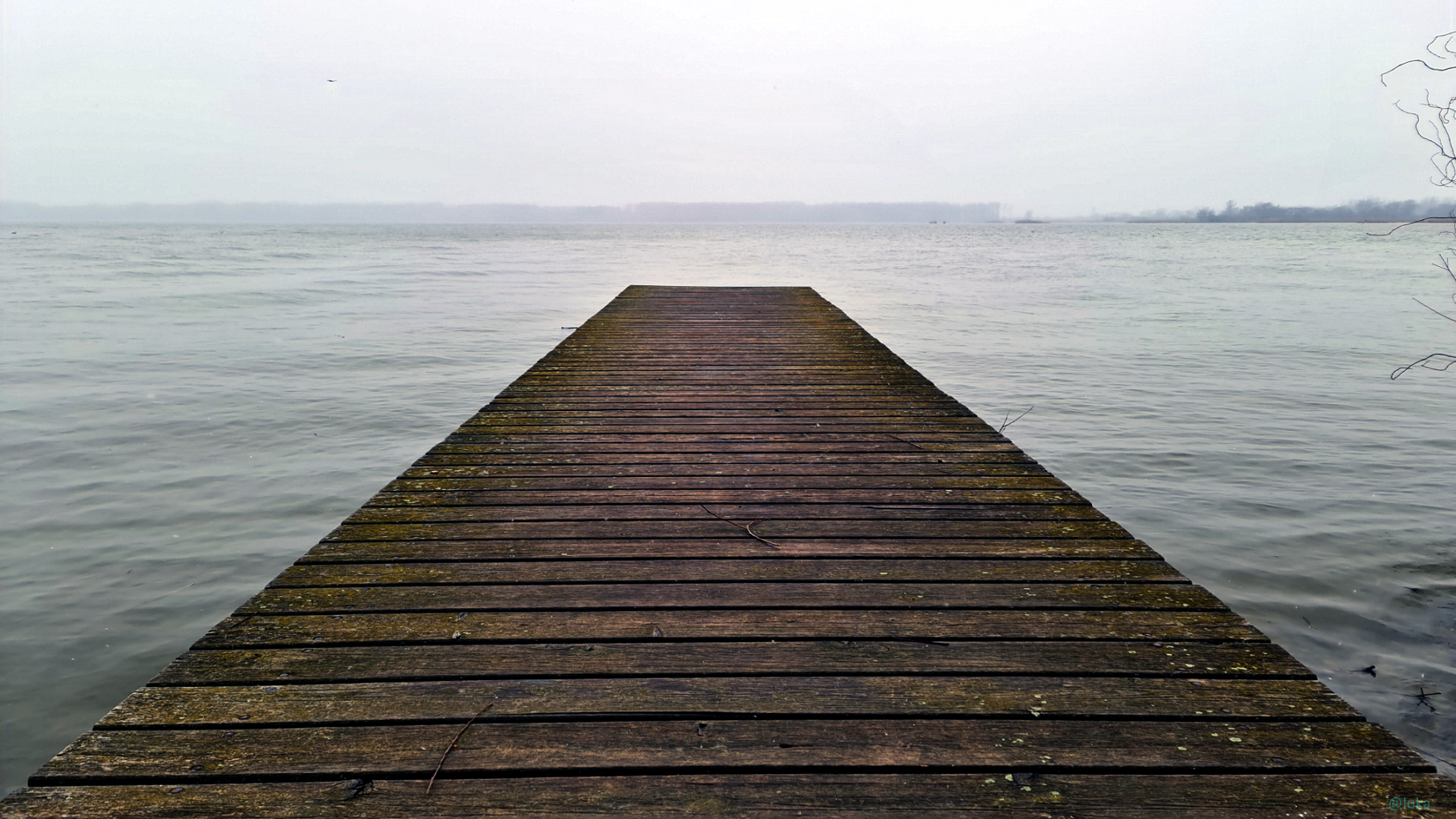 Wooden jetty extending into a calm lake under an overcast sky HD Wallpaper