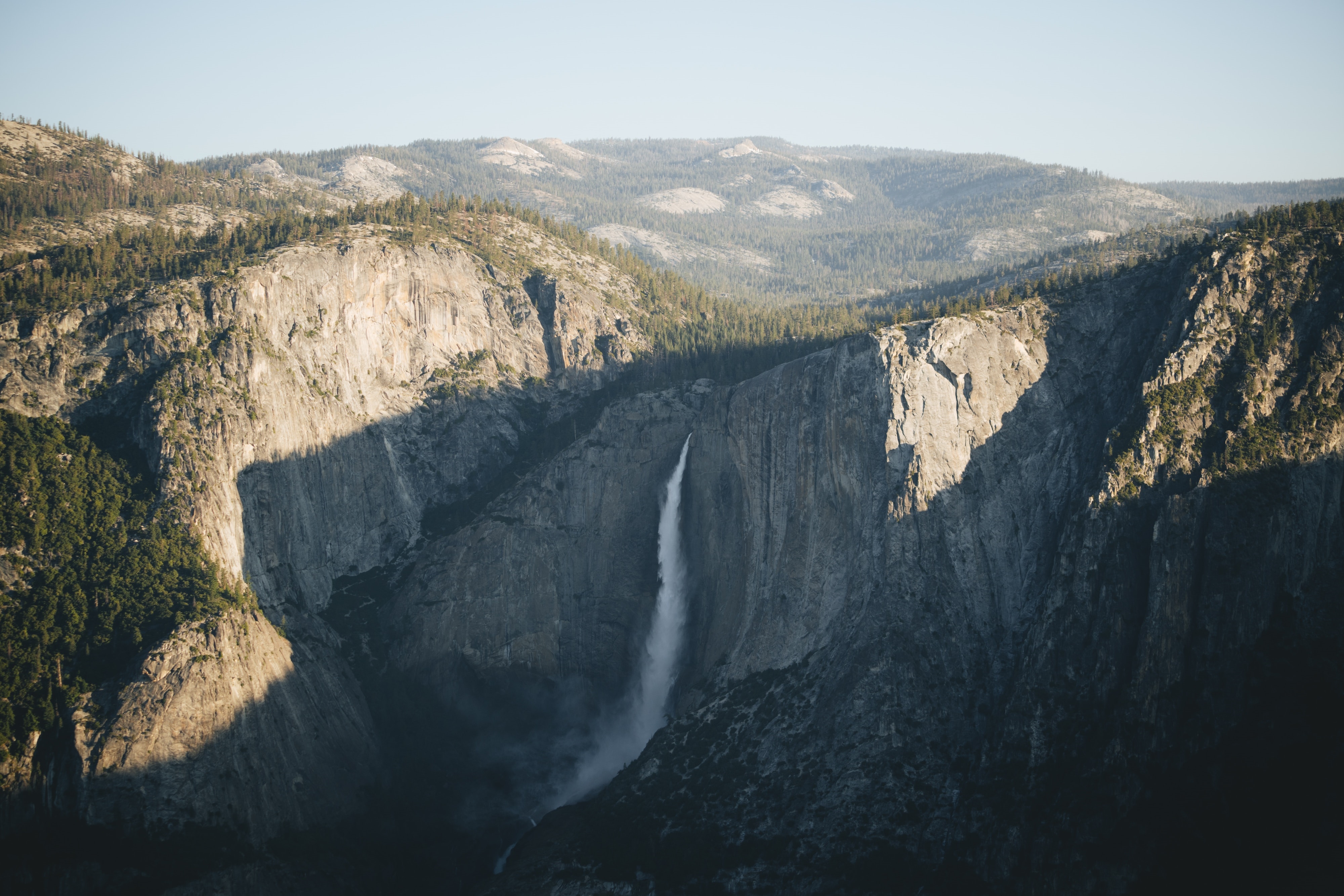 Waterfall cascading down rocky cliffs in a mountain landscape HD Wallpaper