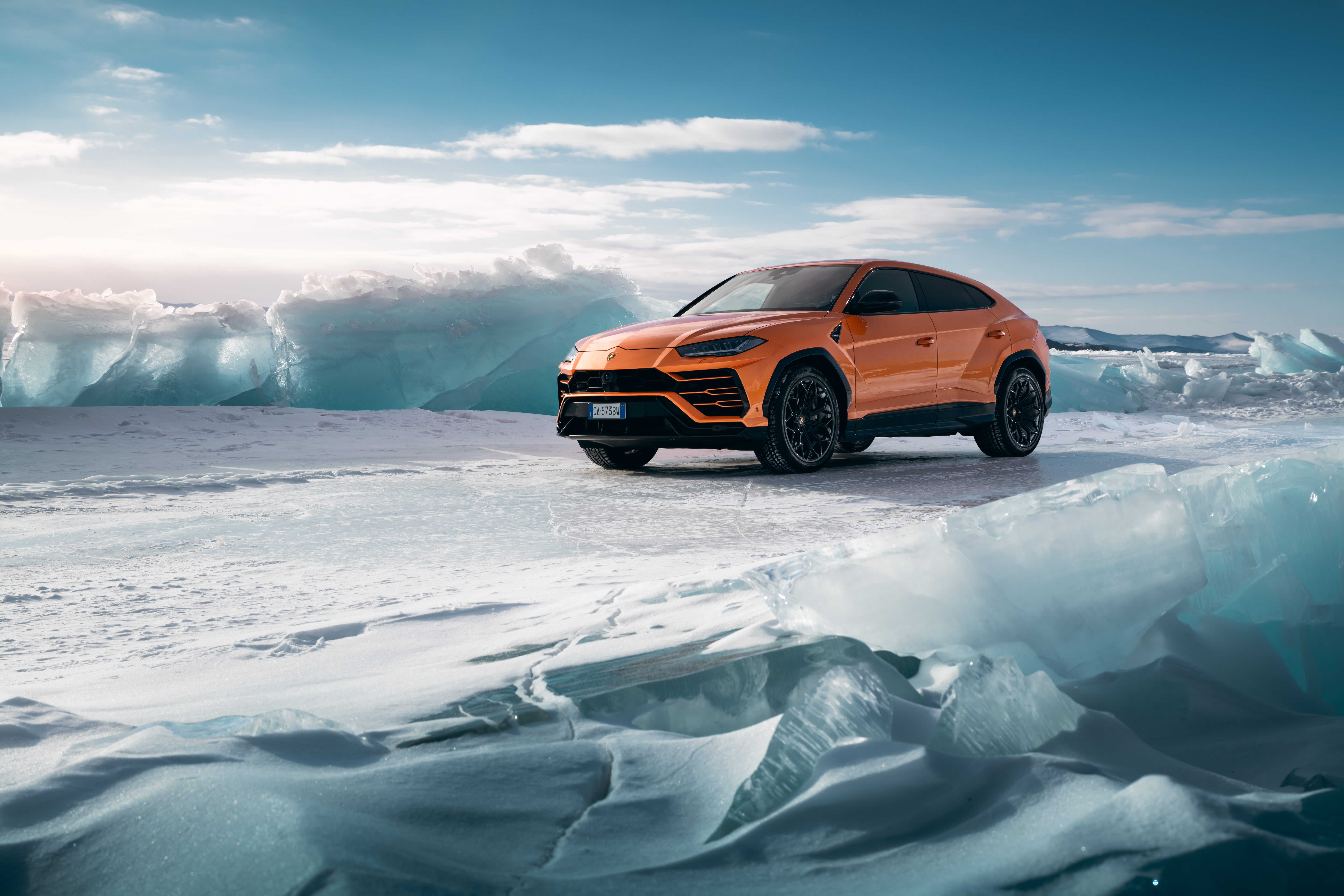 Orange Lamborghini Urus on icy landscape HD Wallpaper