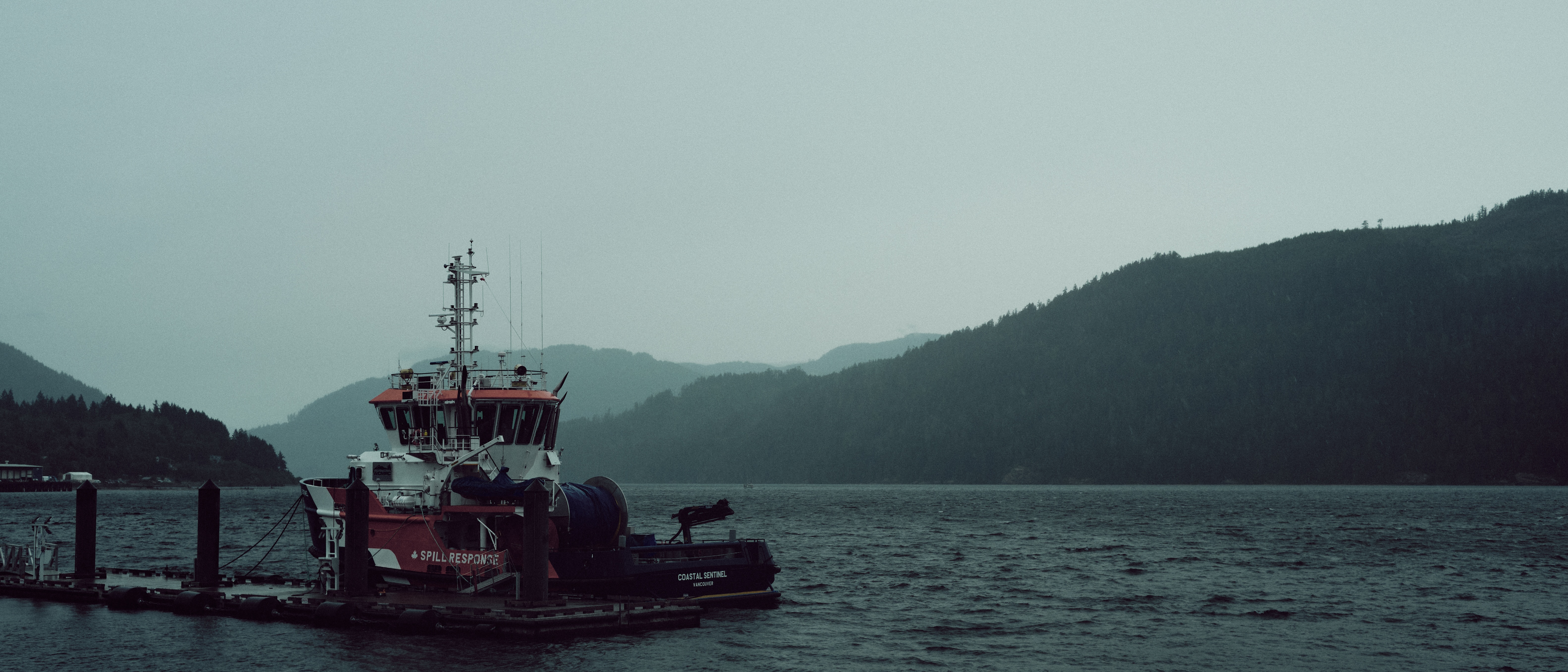 Boat docked at a pier with mountains in the background HD Wallpaper