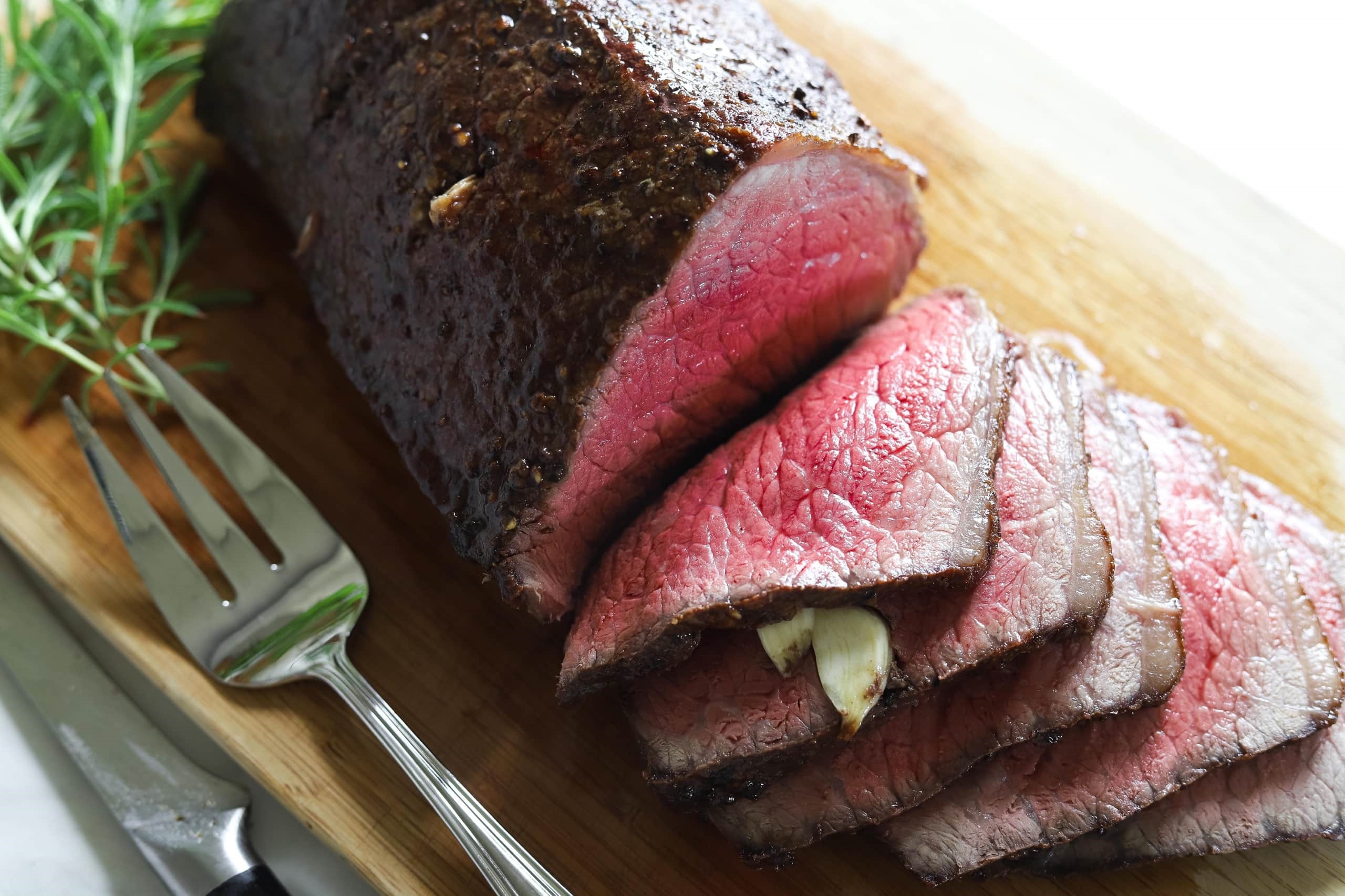Sliced roast beef with garlic on a cutting board HD Wallpaper