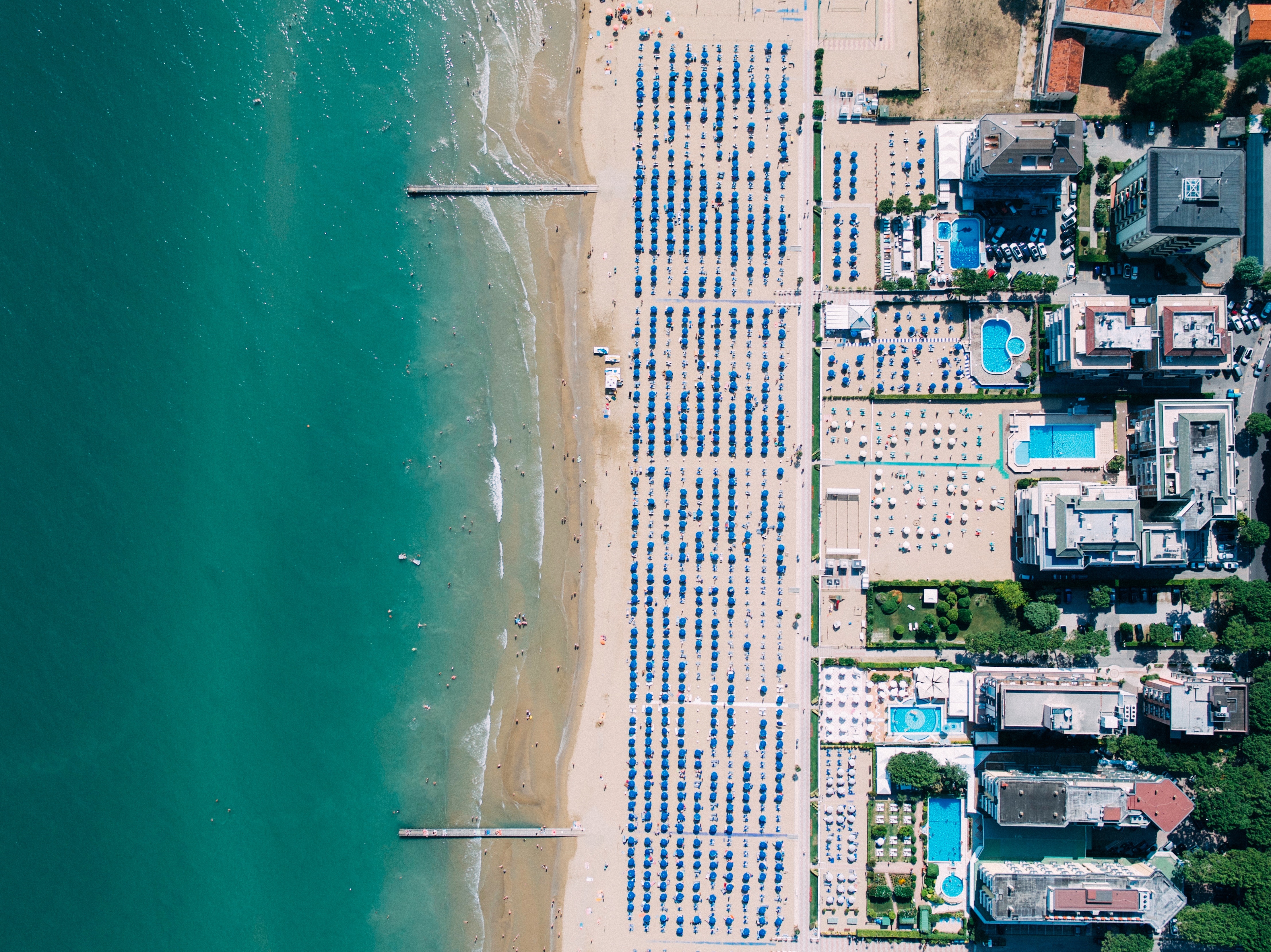 Aerial view of Lido di Jesolo beach with umbrellas and swimming pools HD Wallpaper