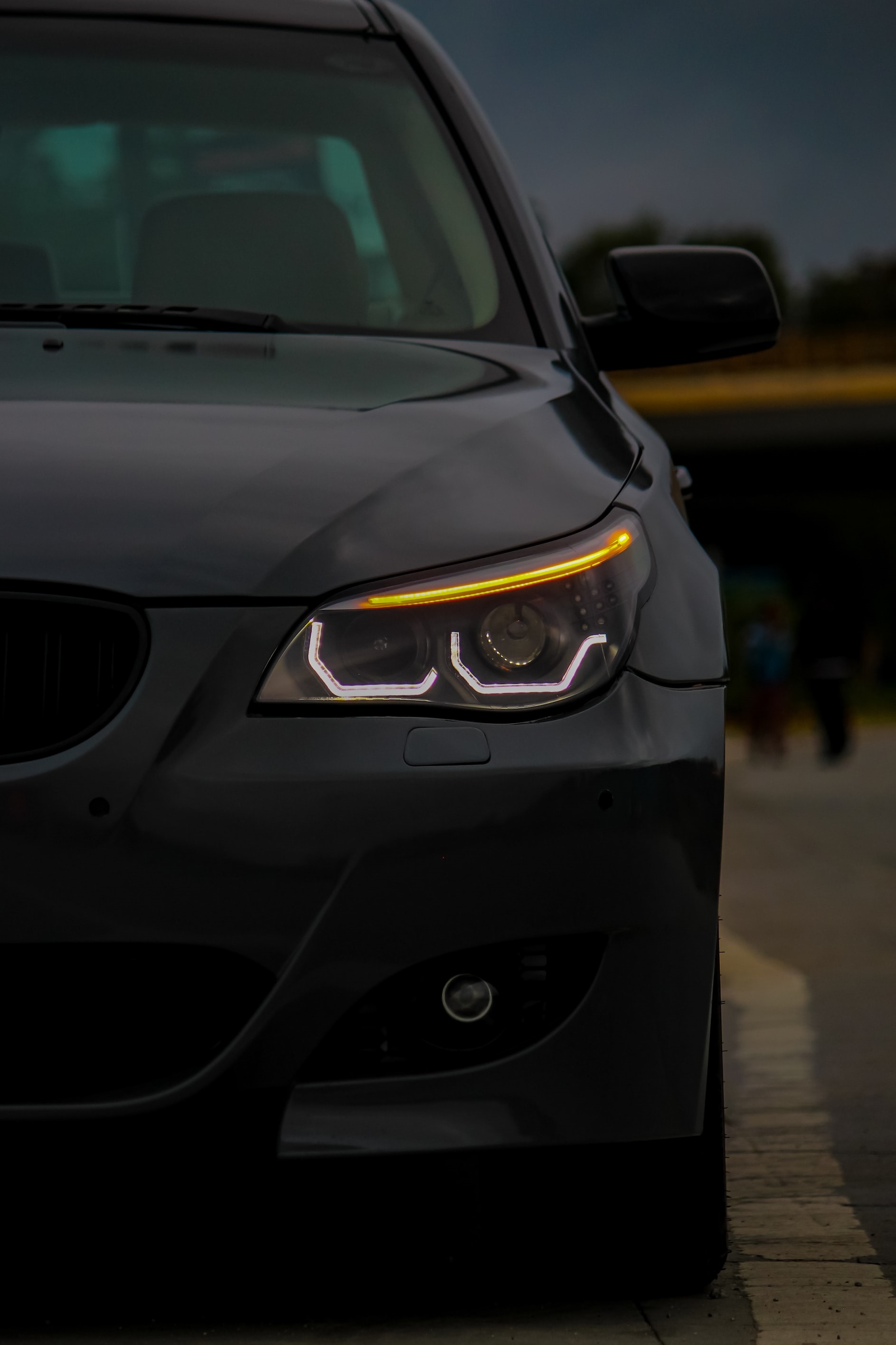 Frontal view of a black BMW car with illuminated headlights HD Phone Wallpaper
