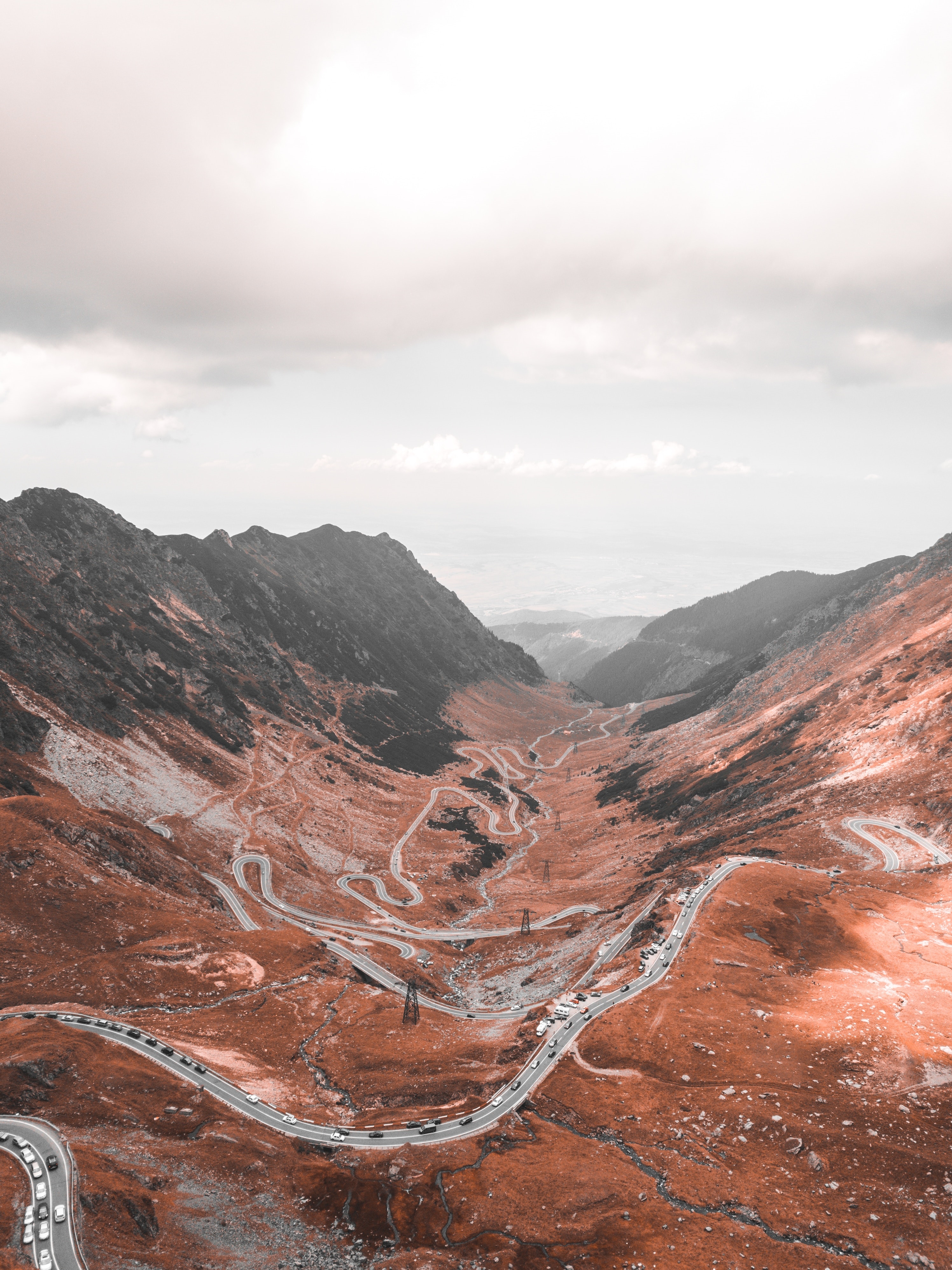 Aerial view of a winding mountain road with cars HD Phone Wallpaper
