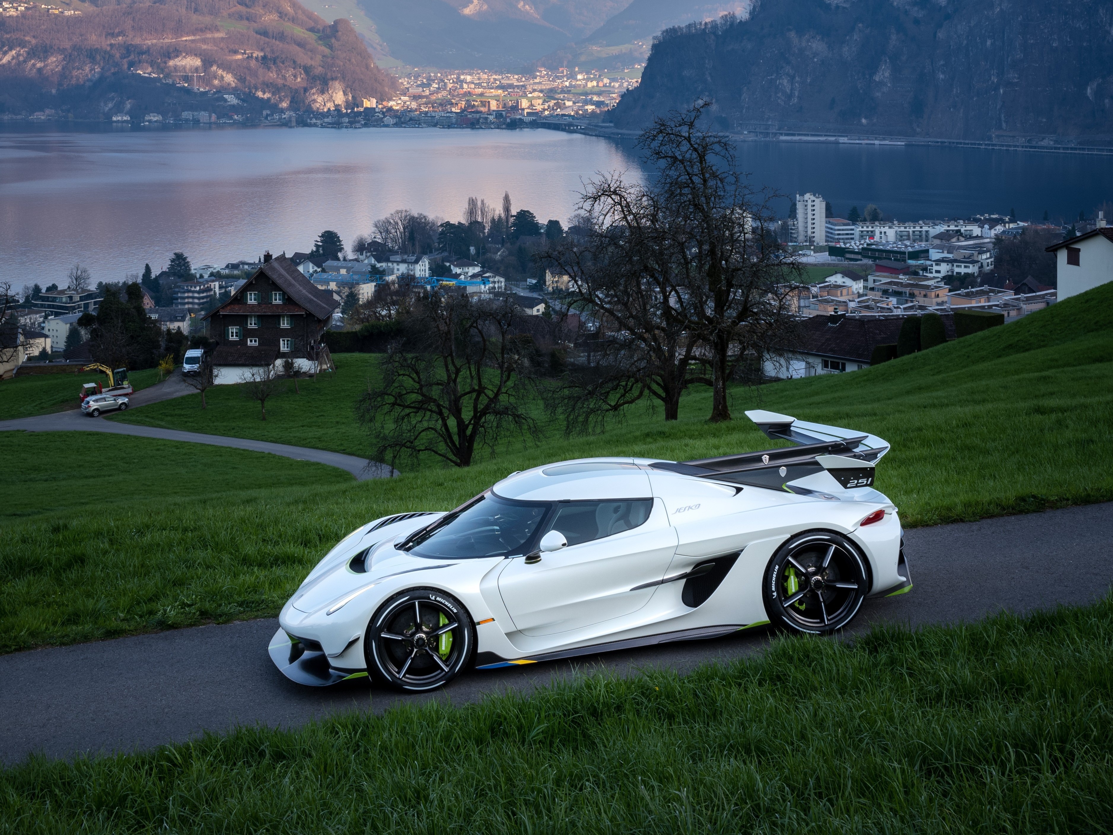 White Koenigsegg Jesko on a road with a village and lake HD Wallpaper