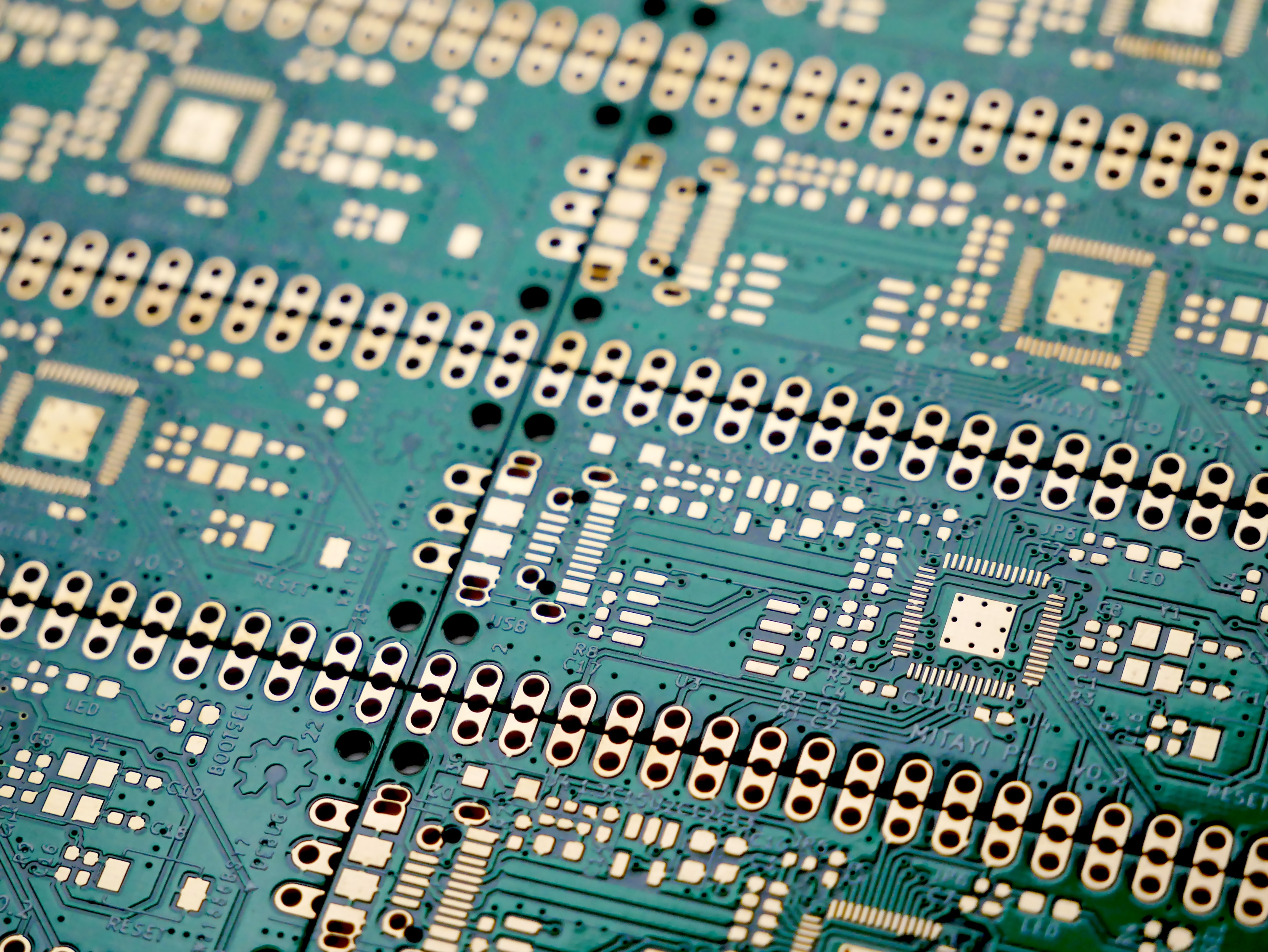 Close-up of a green circuit board with gold connectors HD Wallpaper