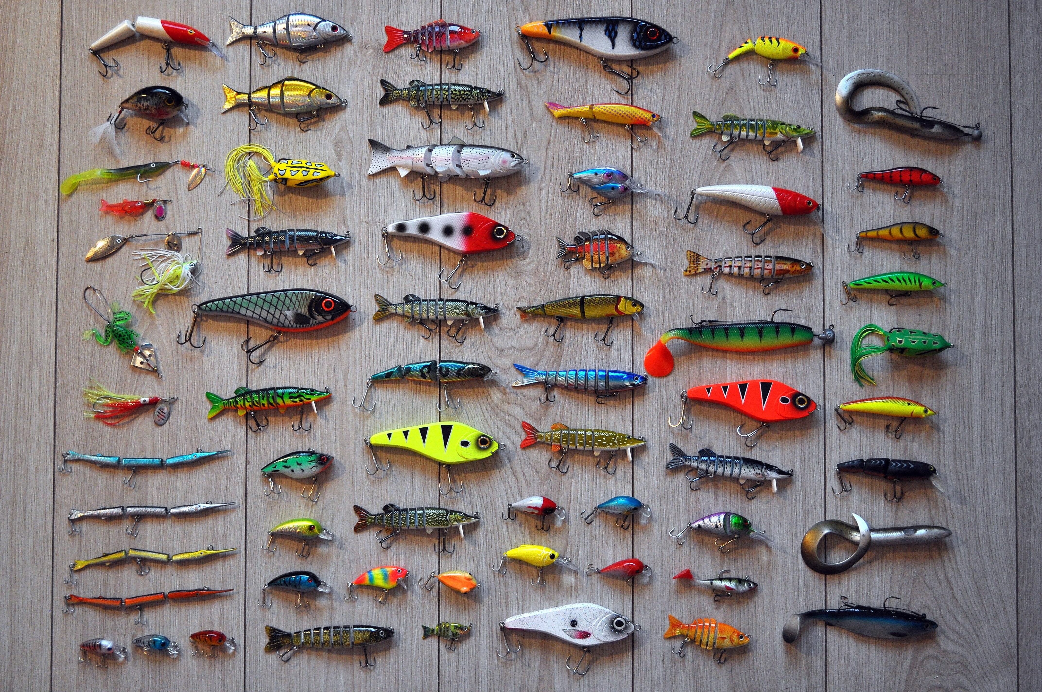 Collection of fishing lures and hooks on a wooden surface HD Wallpaper