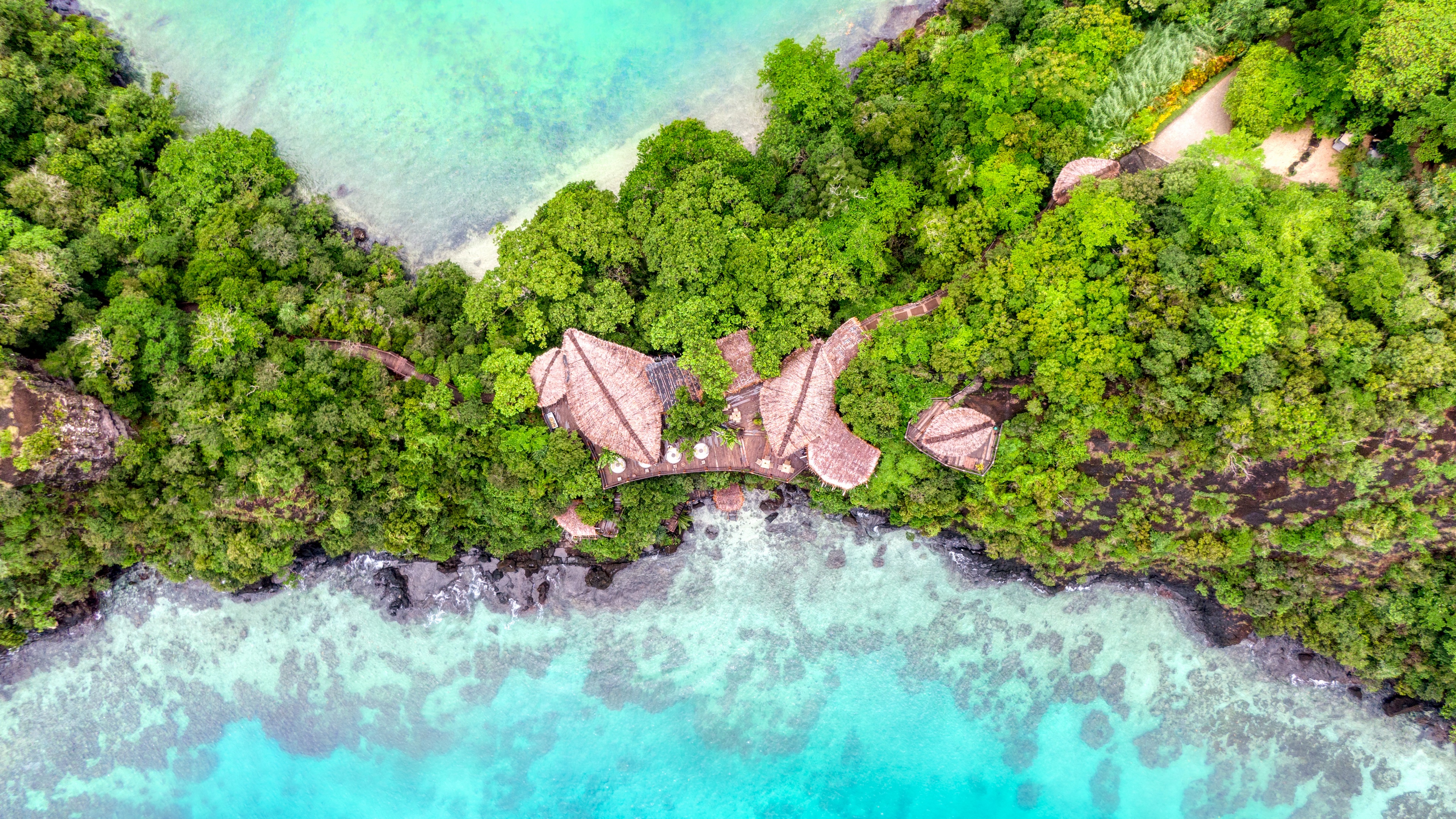 Aerial view of a resort in Fiji surrounded by forest and water HD Wallpaper