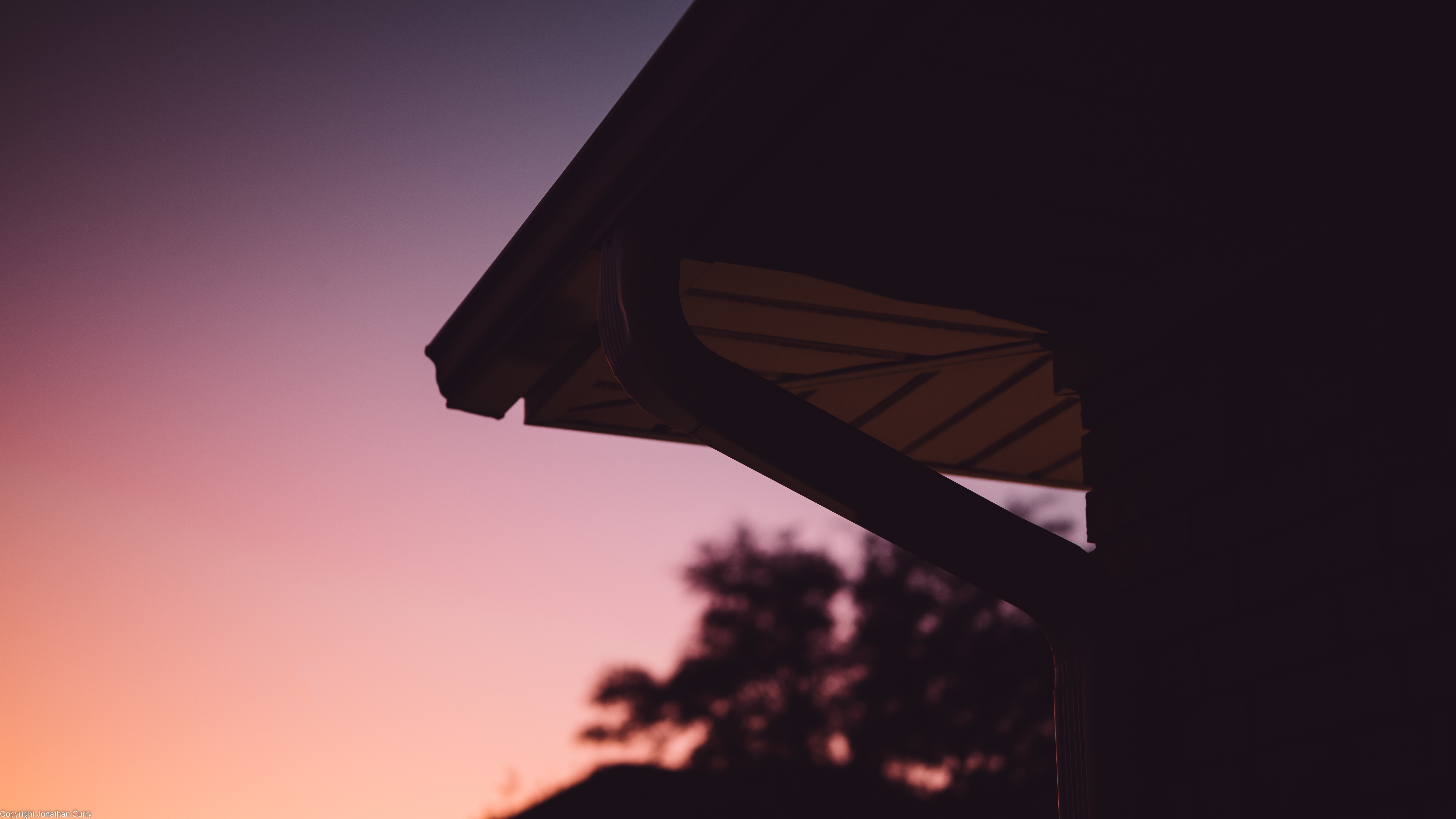 Silhouette of a house roof against a sunset gradient HD Wallpaper