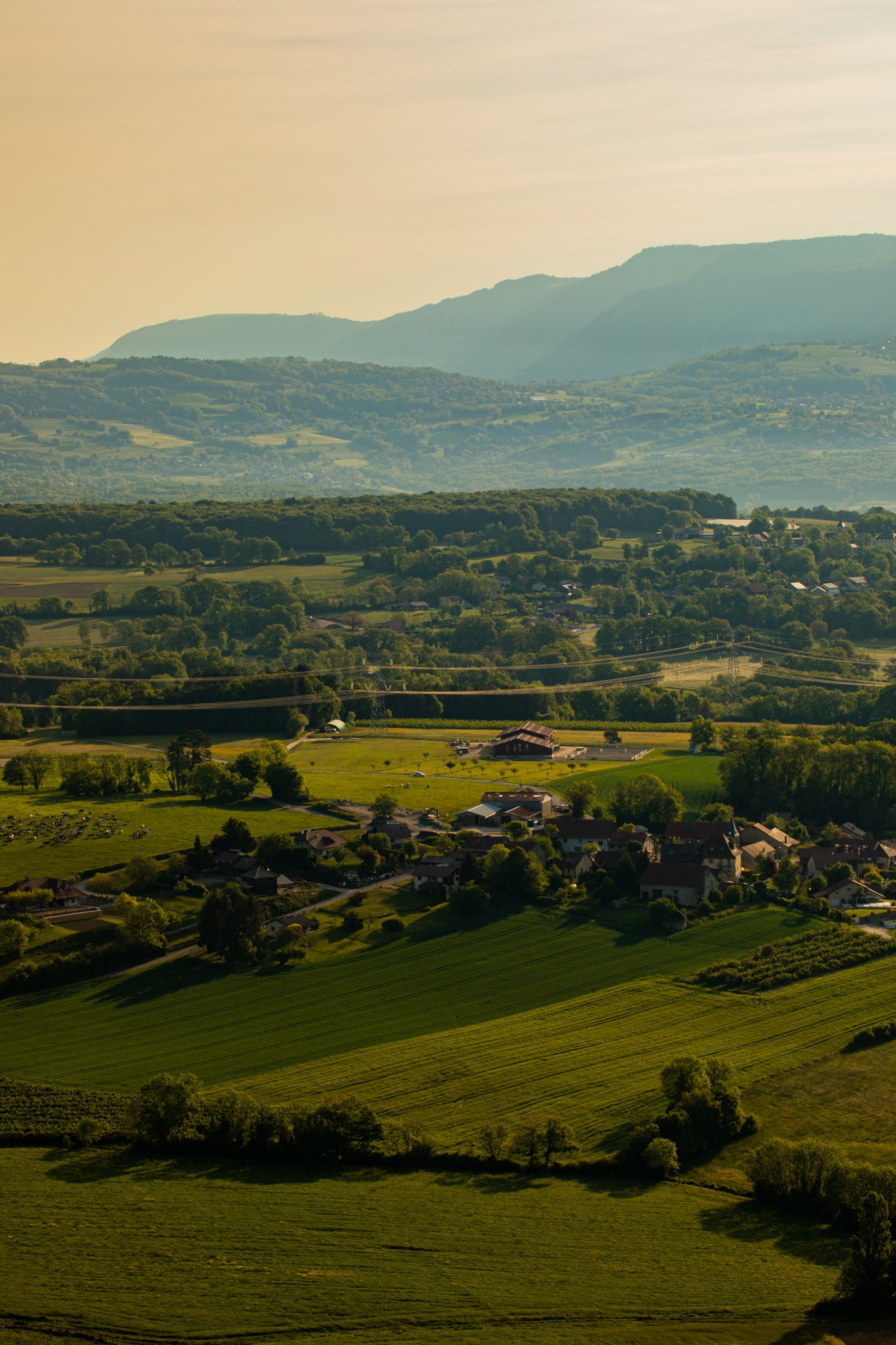 Green fields and village nestled in rolling hills HD Phone Wallpaper