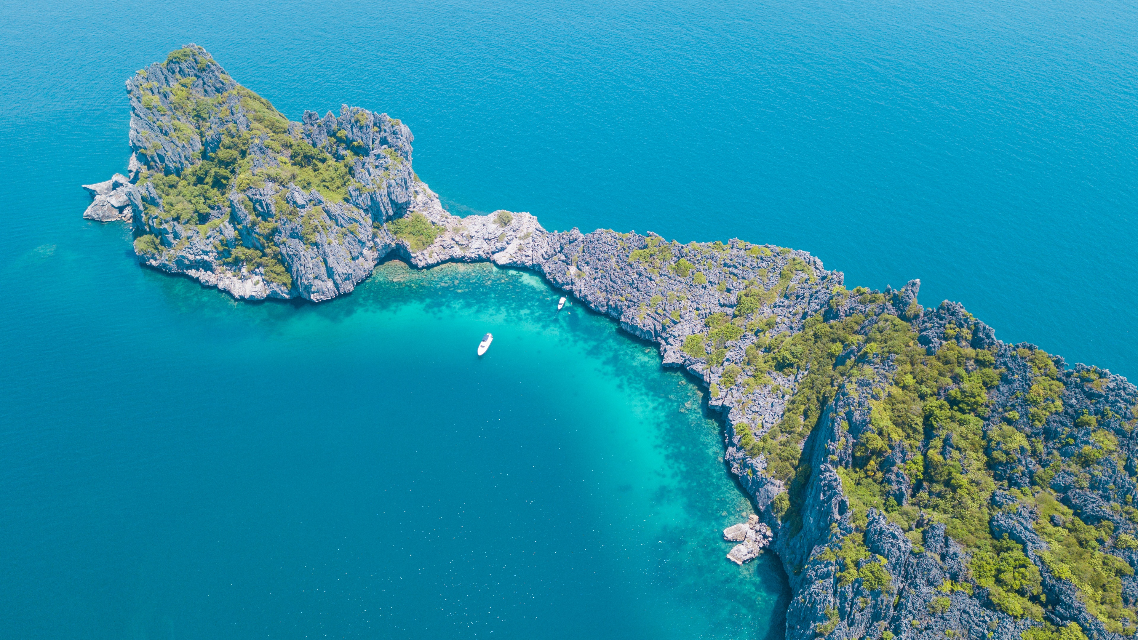 Aerial view of a rocky island with trees in the sea HD Wallpaper