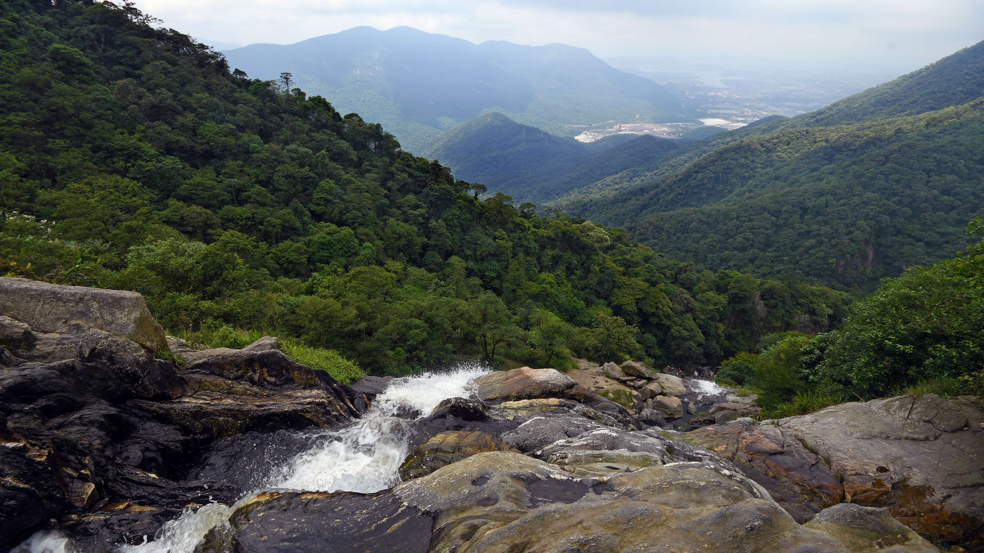 4K waterfall flowing over rocks in a mountain landscape HD Wallpaper