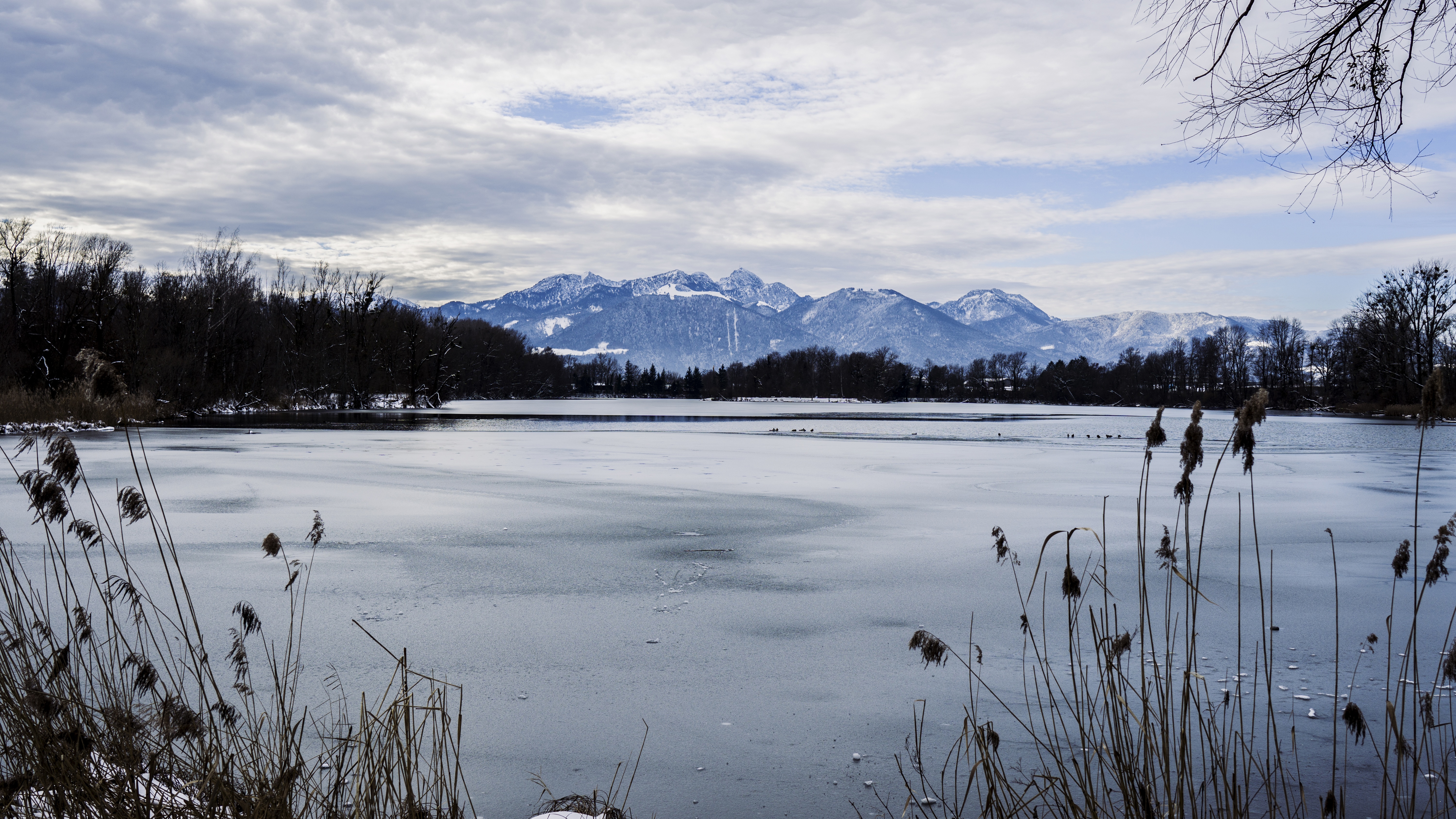 Frozen lake with snow-capped mountains in the background HD Wallpaper