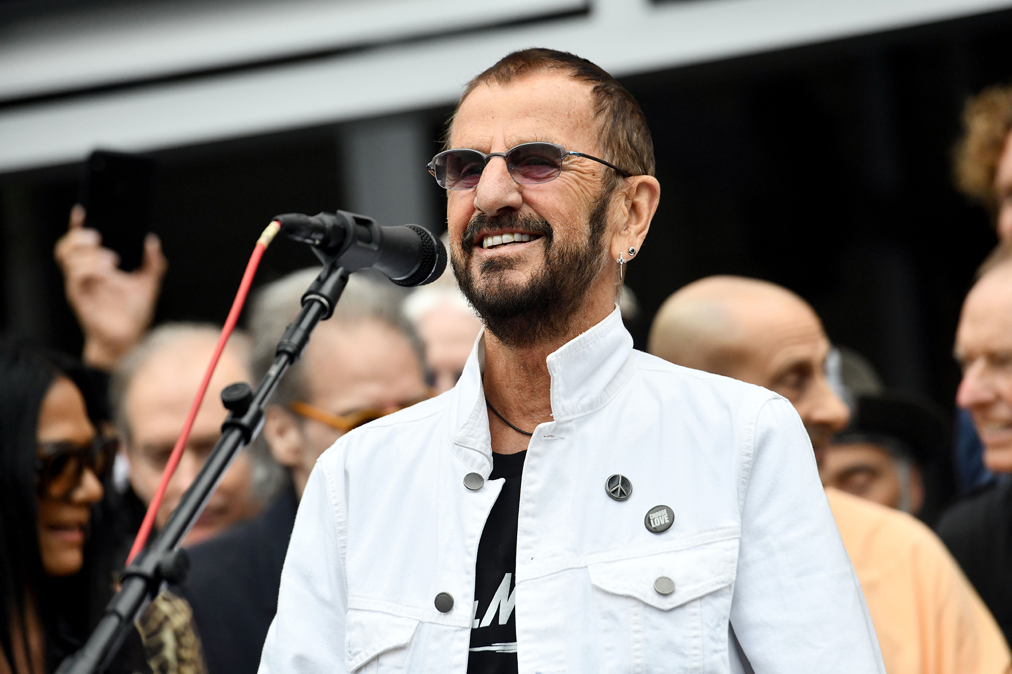 Ringo Starr speaks at a microphone HD Wallpaper