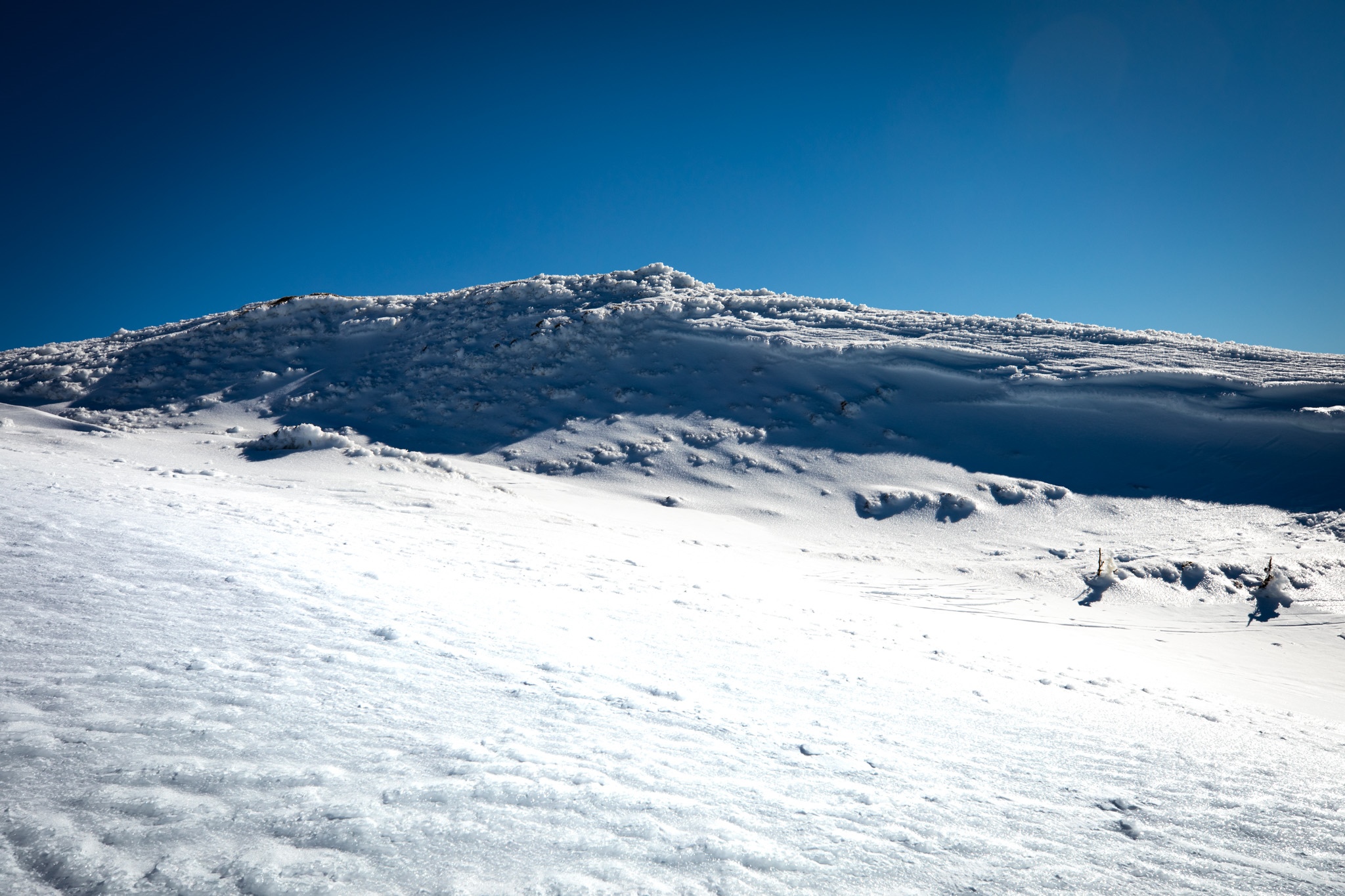 Snowy mountain ridge under a clear blue sky HD Wallpaper