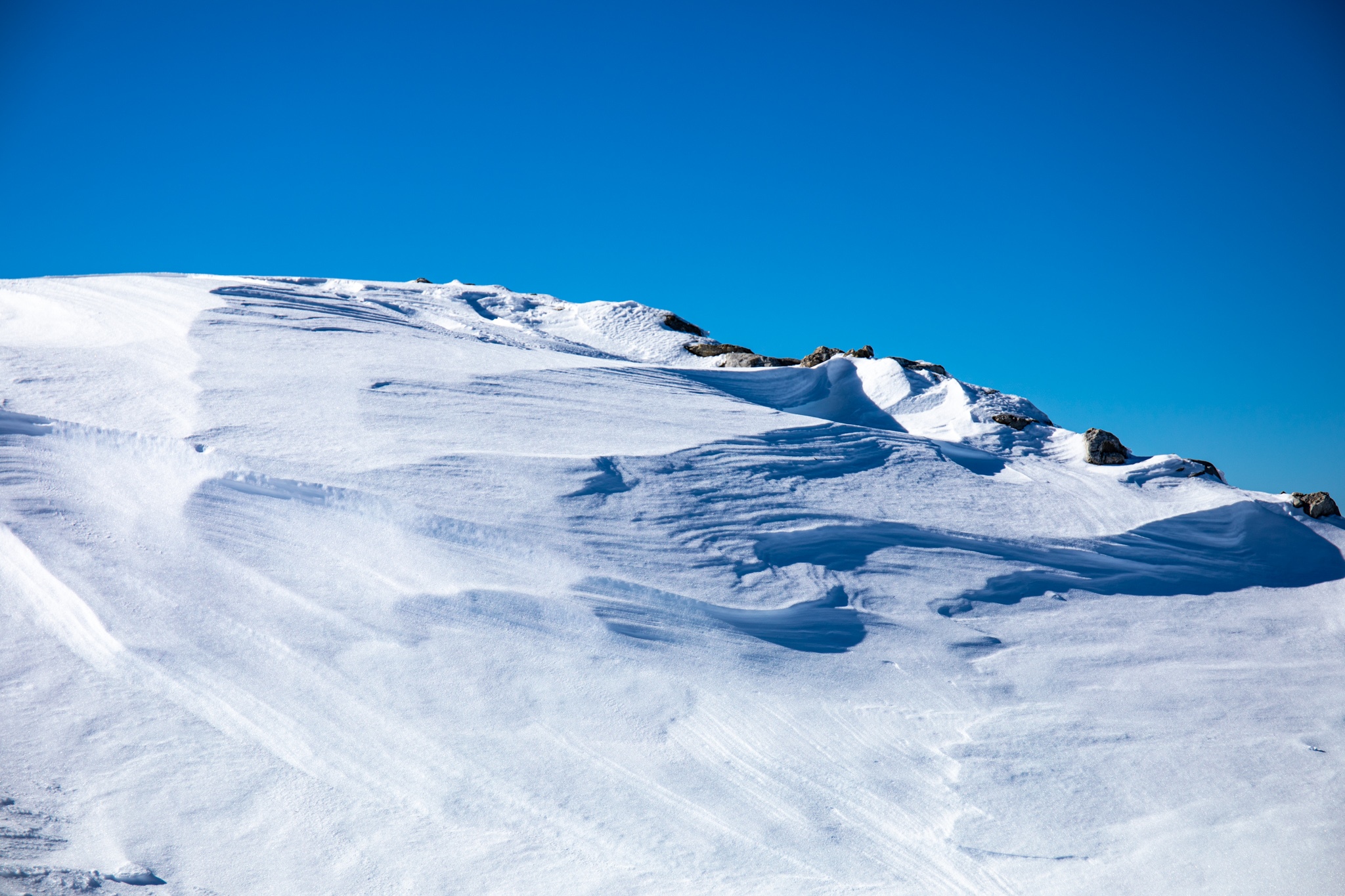 Snowy mountain ridge under a clear blue sky HD Wallpaper