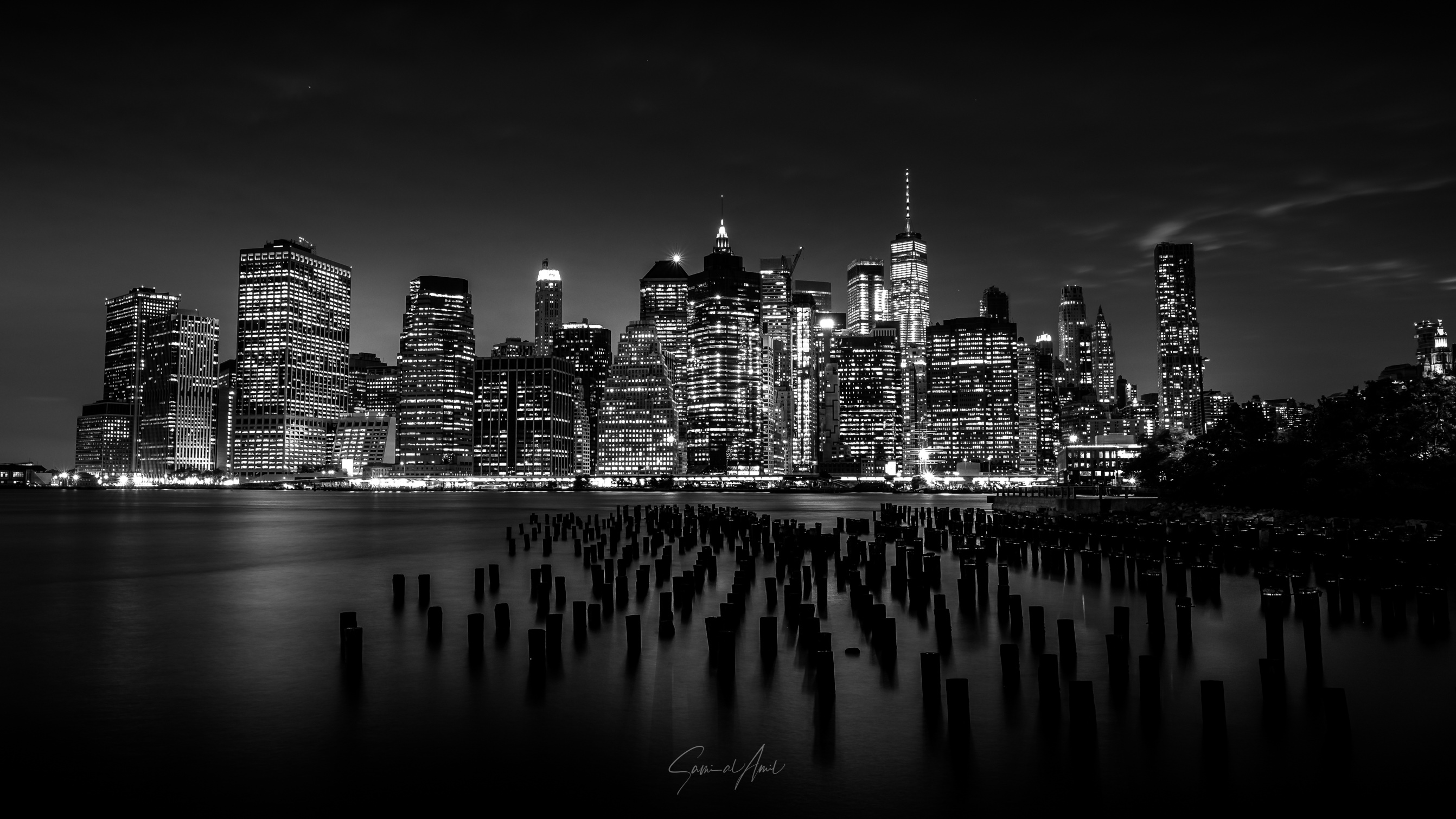 New York City skyline at night with water and pilings HD Wallpaper