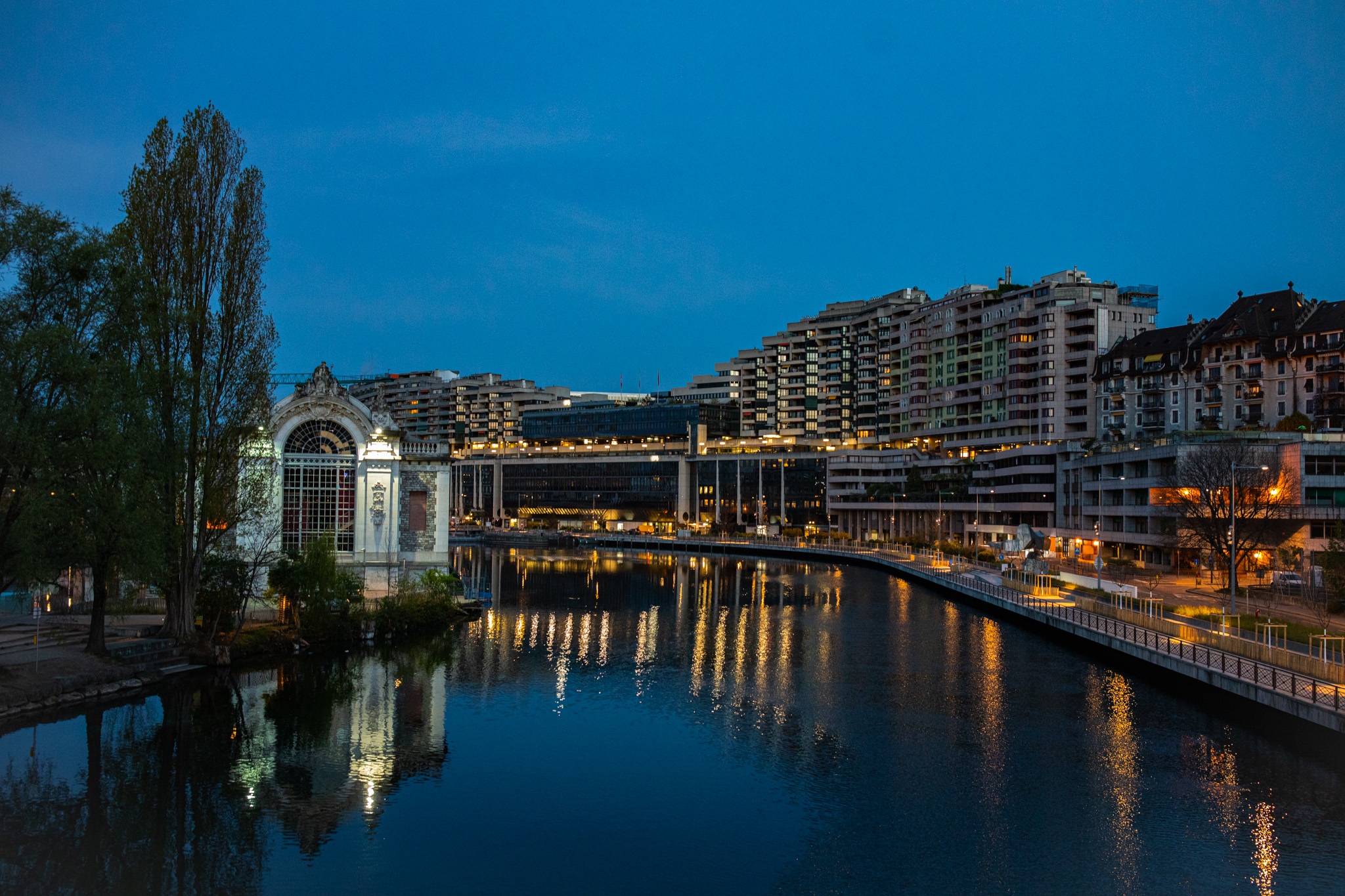 City buildings and a river at dusk with reflections HD Wallpaper