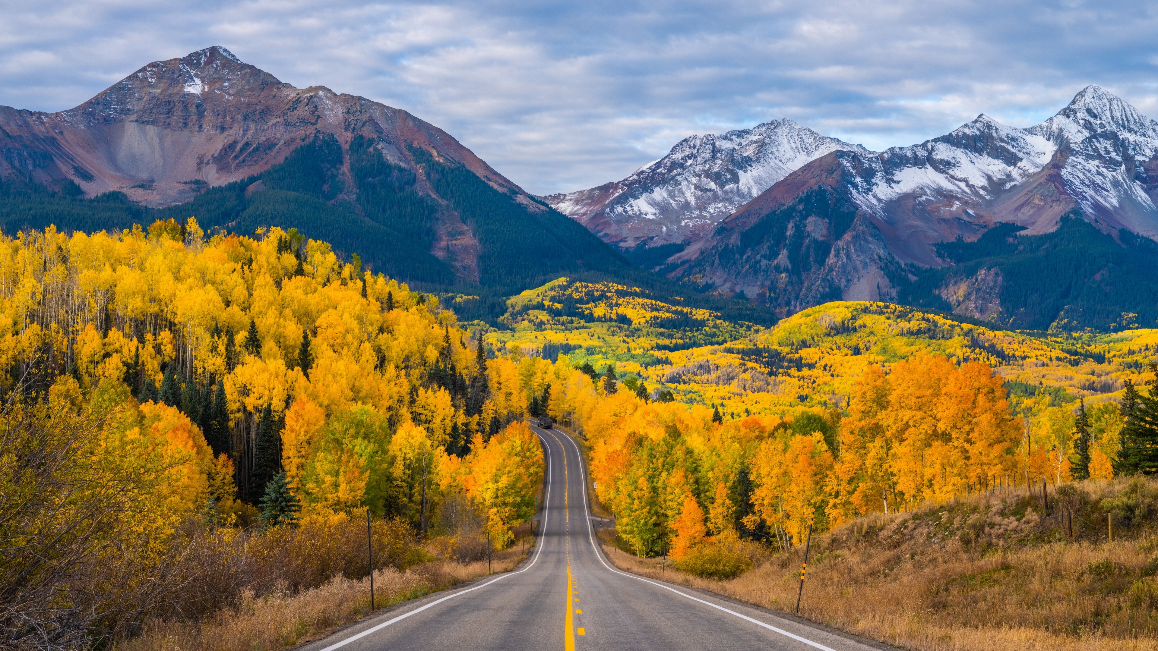 Road through autumn forest to snow-capped mountains in Colorado HD Wallpaper