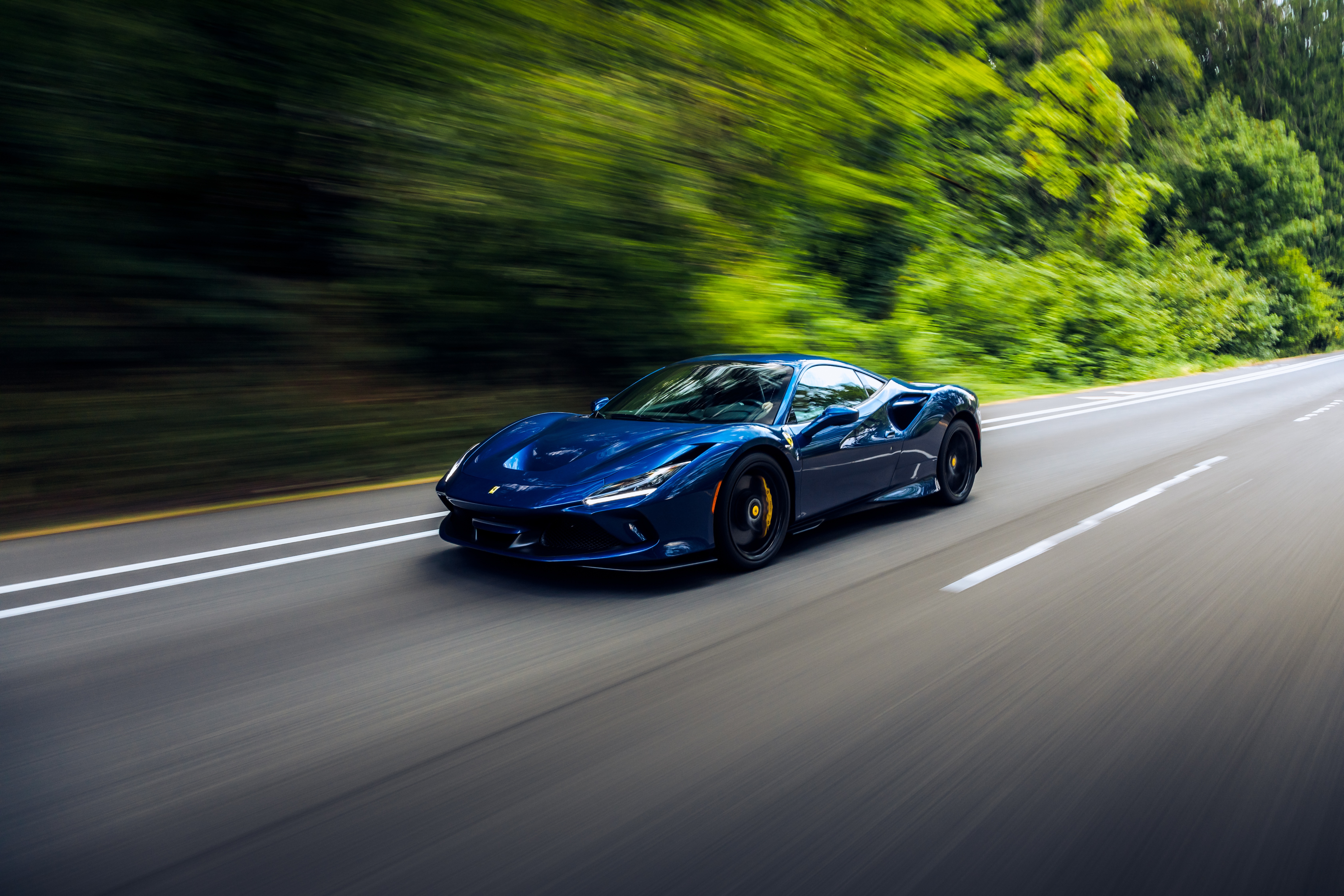 Blue Ferrari F8 Tributo driving on a road HD Wallpaper