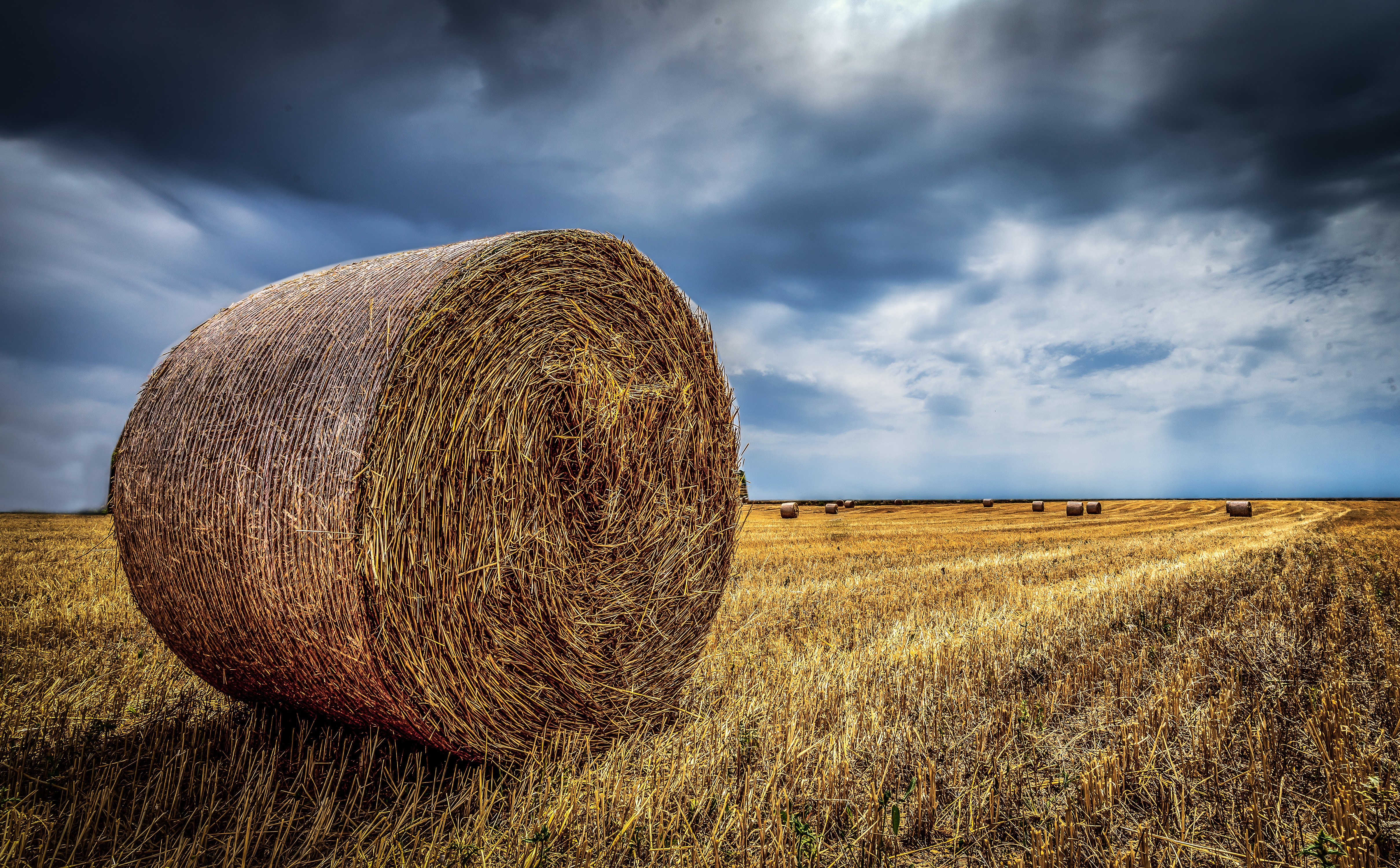 4K Hay Bale in a Field Under Stormy Sky HD Wallpaper