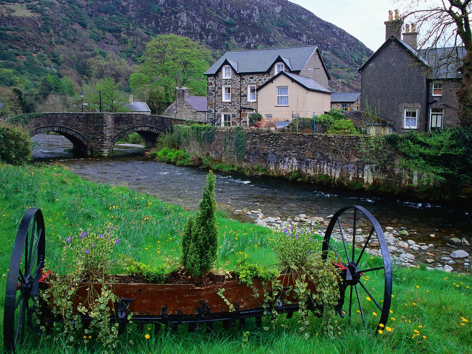 Stone bridge over a river with houses and mountains HD Wallpaper