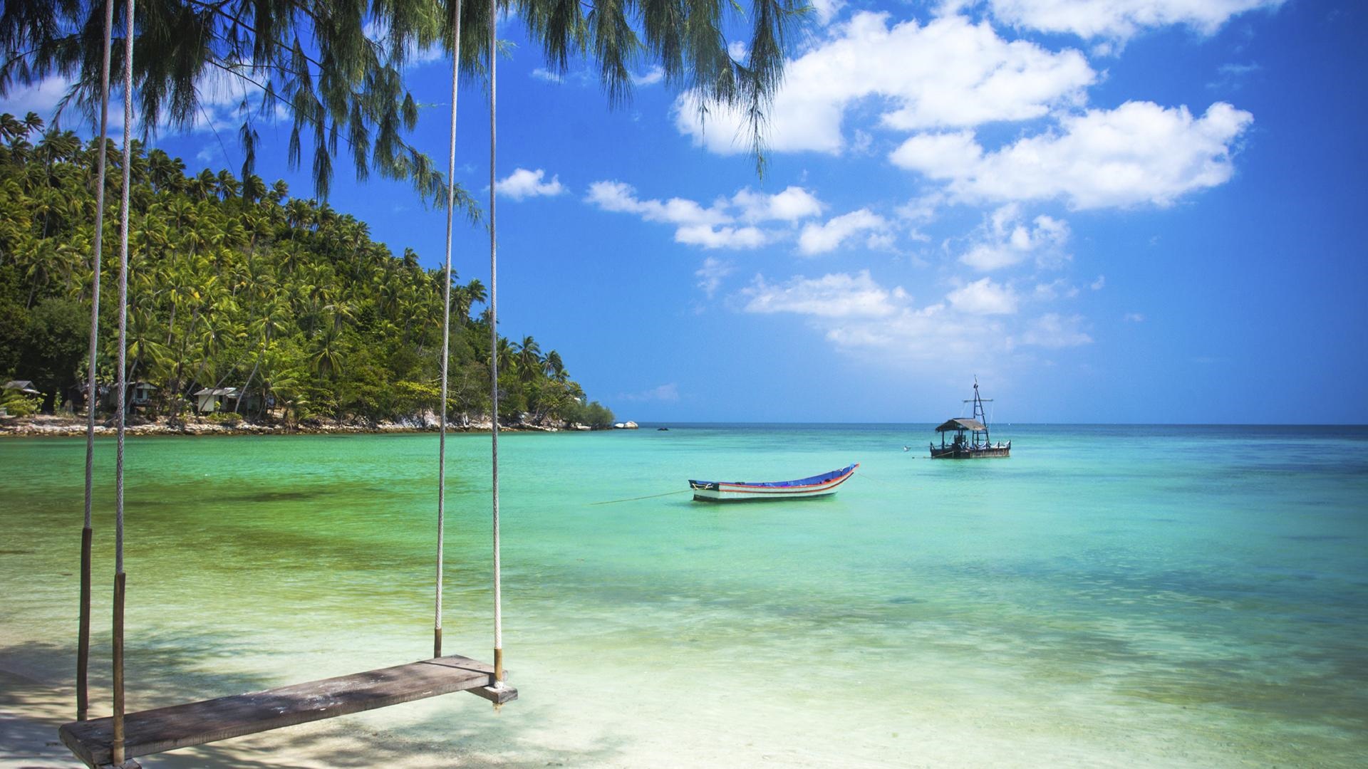 Tropical beach with swing and boats HD Wallpaper